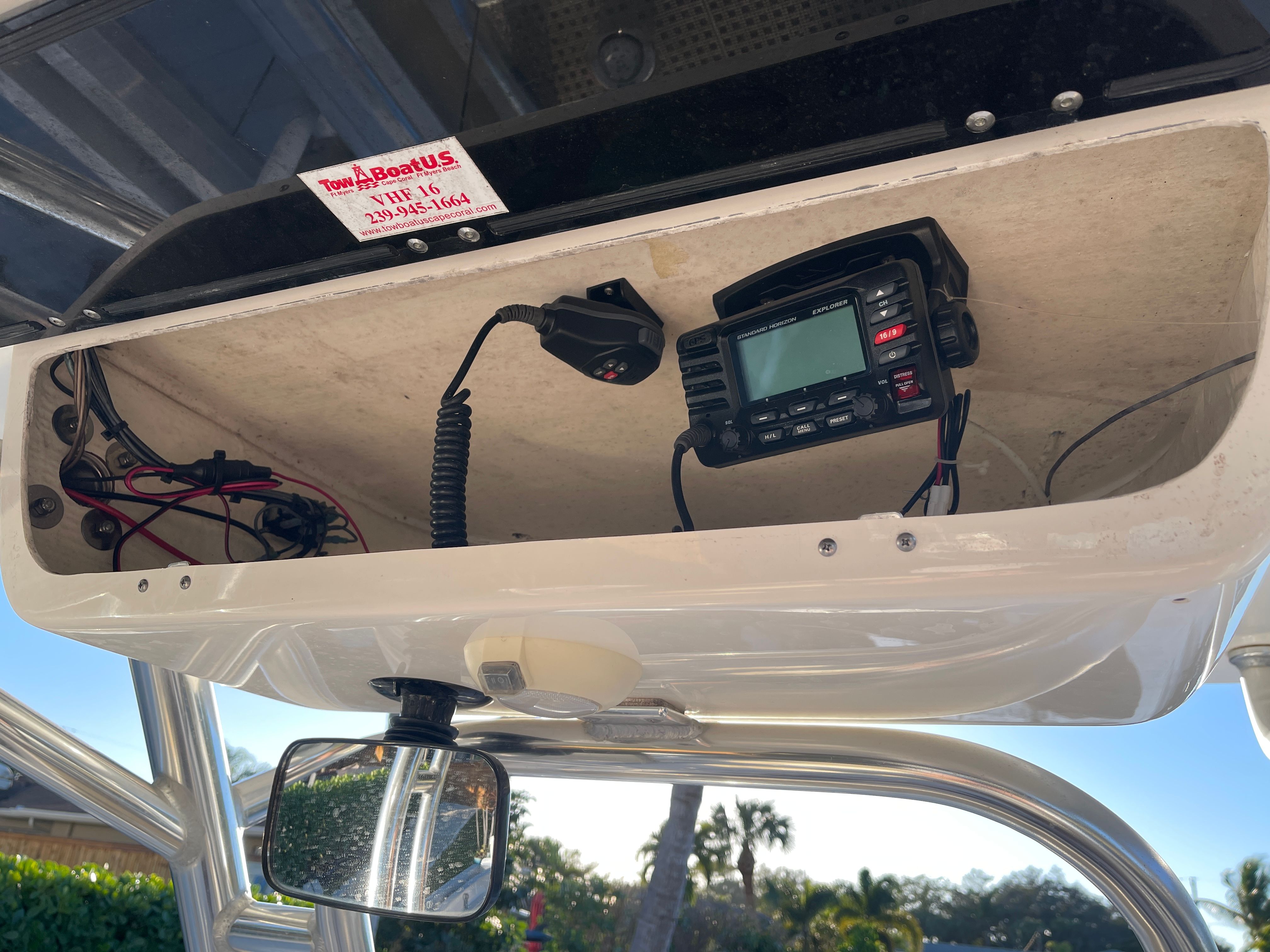 An open storage compartment with a radio and wires on a boat.