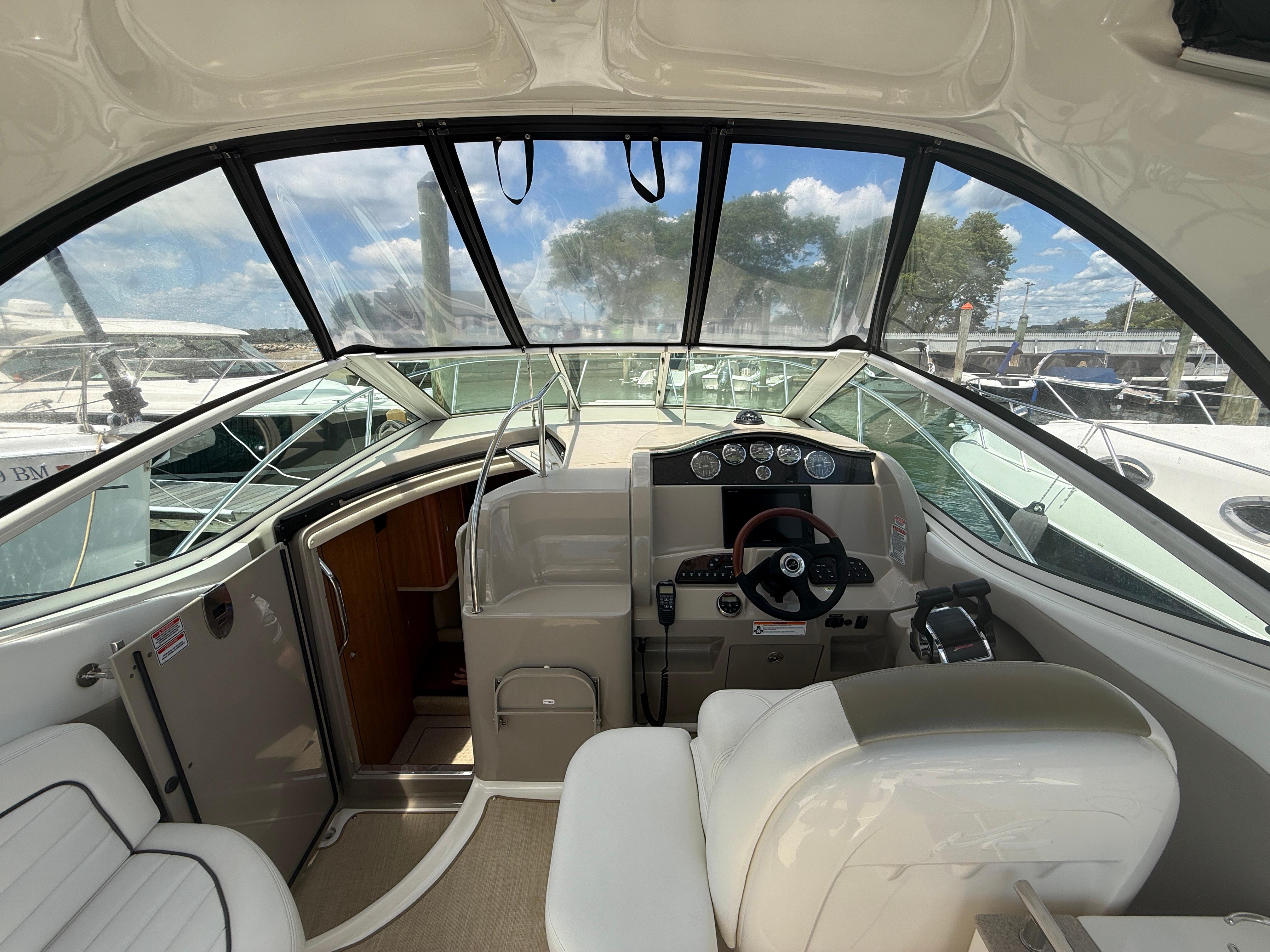 2006 Sea Ray 290 Sundancer cockpit with steering wheel and dashboard, docked at marina.