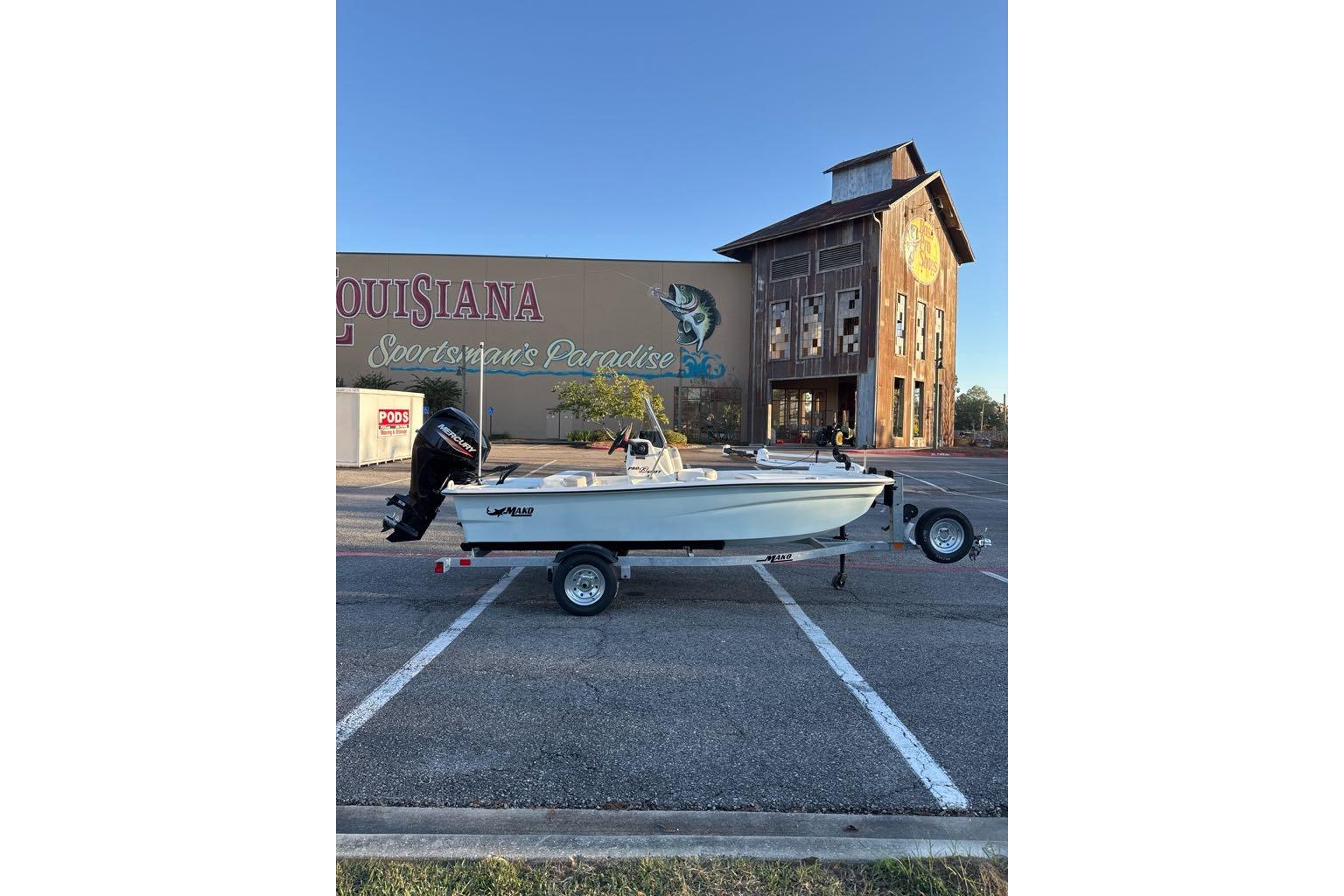 2026 Mako Pro Skiff 13 CC boat on trailer in parking lot, Louisiana backdrop.