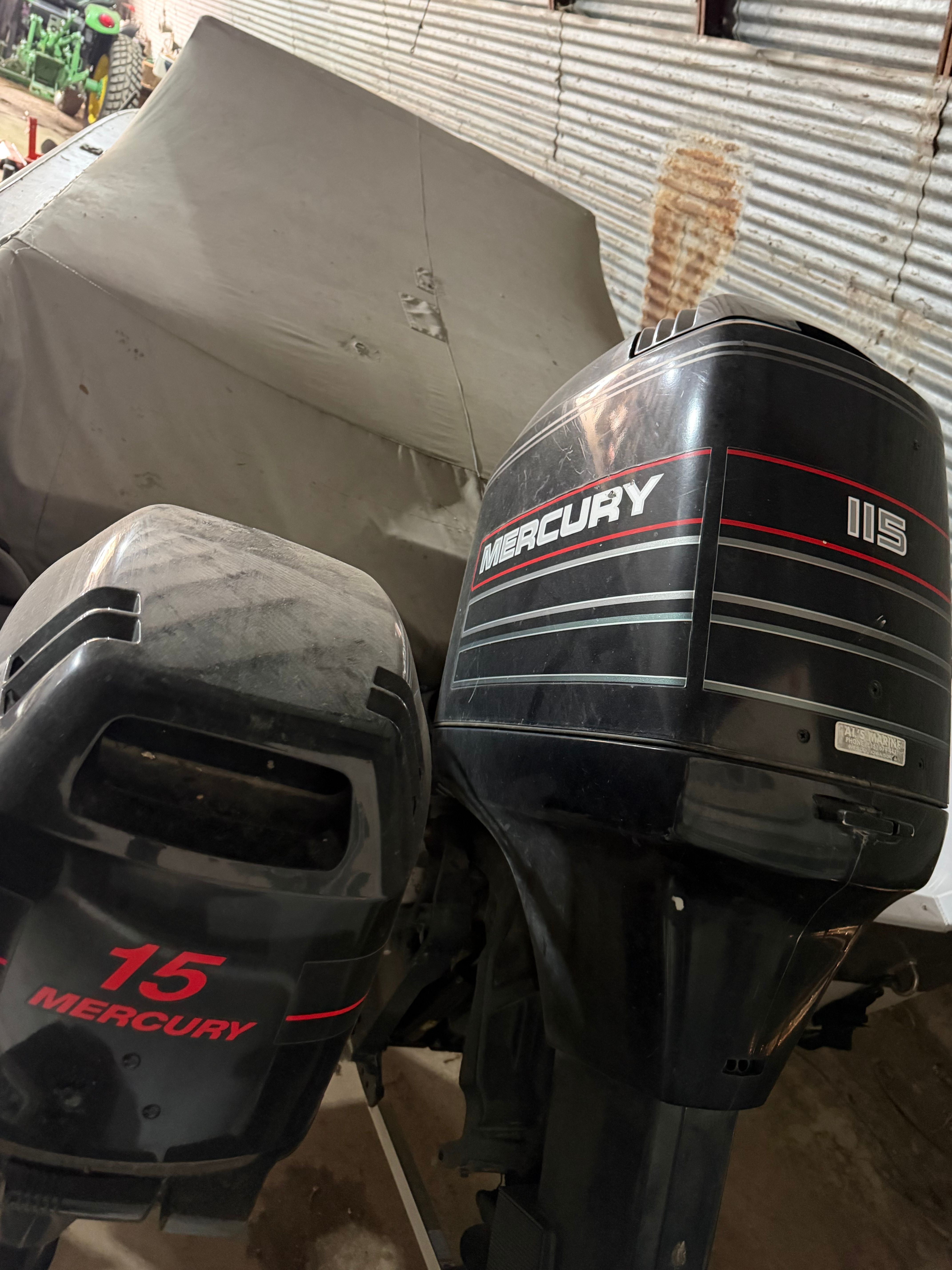 Two Mercury outboard motors beside a covered boat.