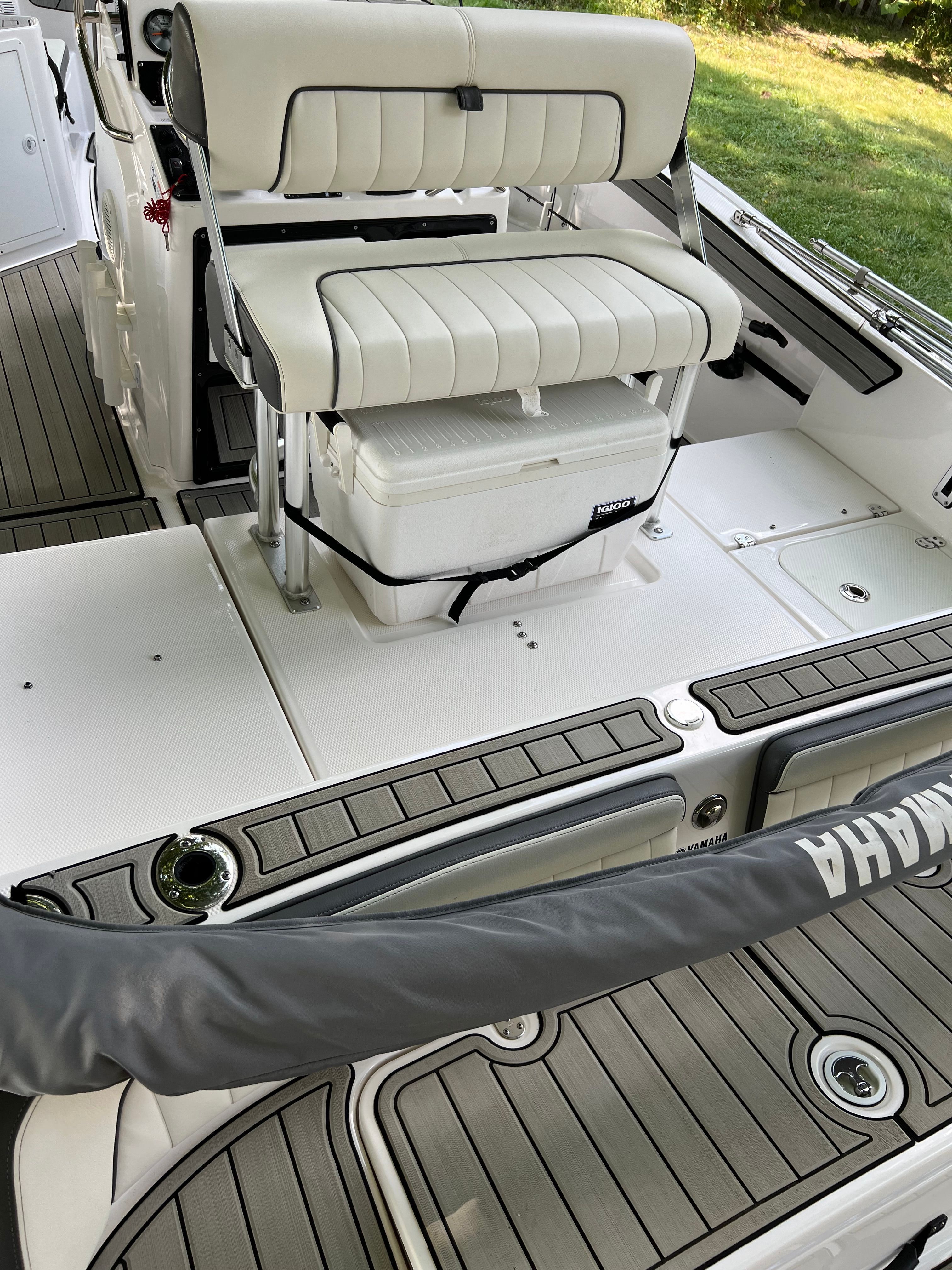 Interior of 2022 Yamaha Boats 210 FSH Deluxe with bench seat and cooler.