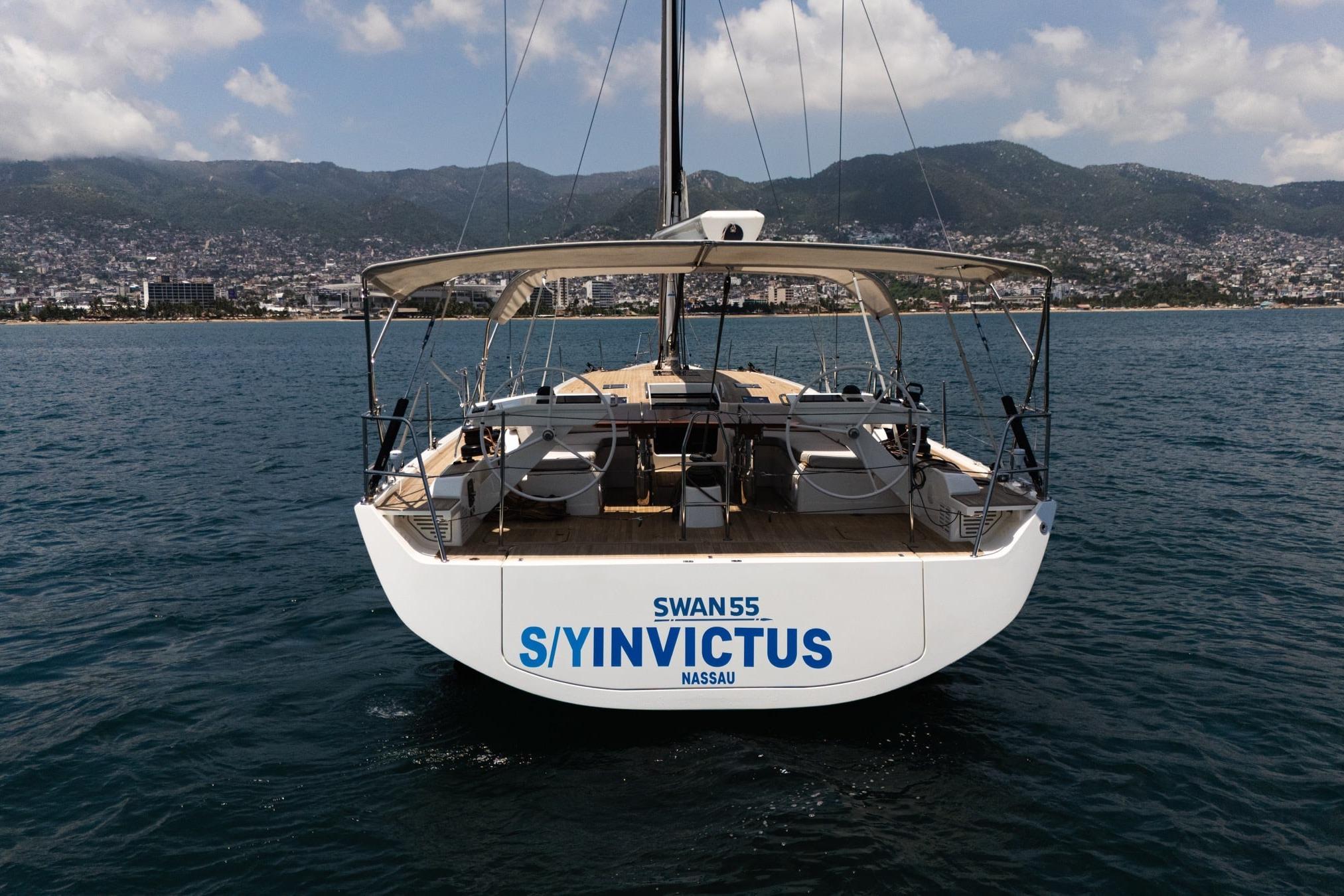 Nautor Swan 55 yacht "Invictus" on water, 2023 model, with scenic coastal backdrop.