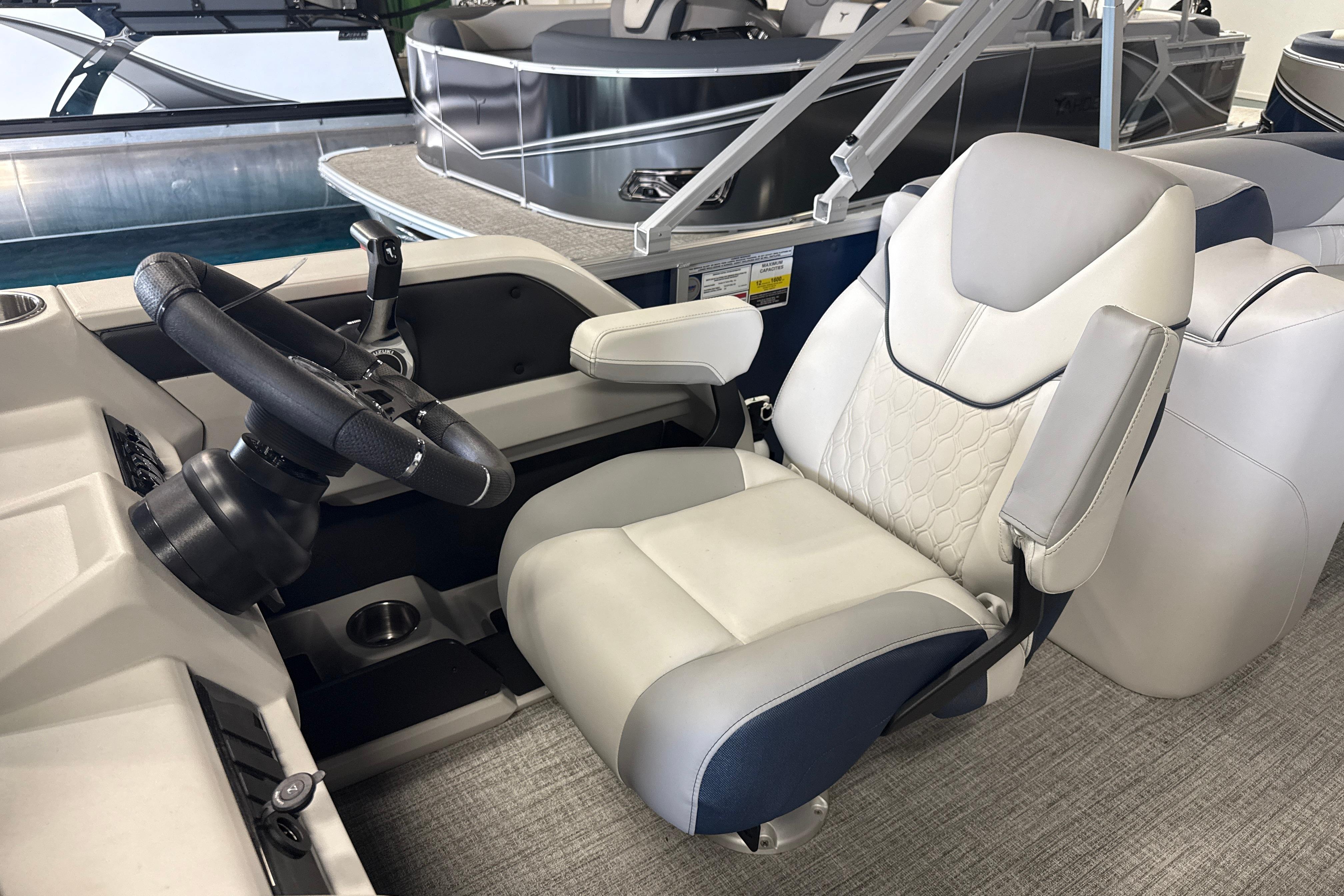 2026 Tahoe Pontoon LTZ Quad Lounger captain's chair and steering wheel in a showroom.