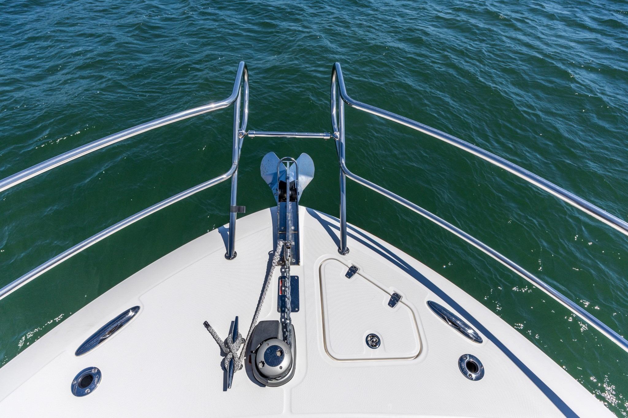 Bow of 2023 Boston Whaler 405 Conquest, featuring anchor and railing over water.