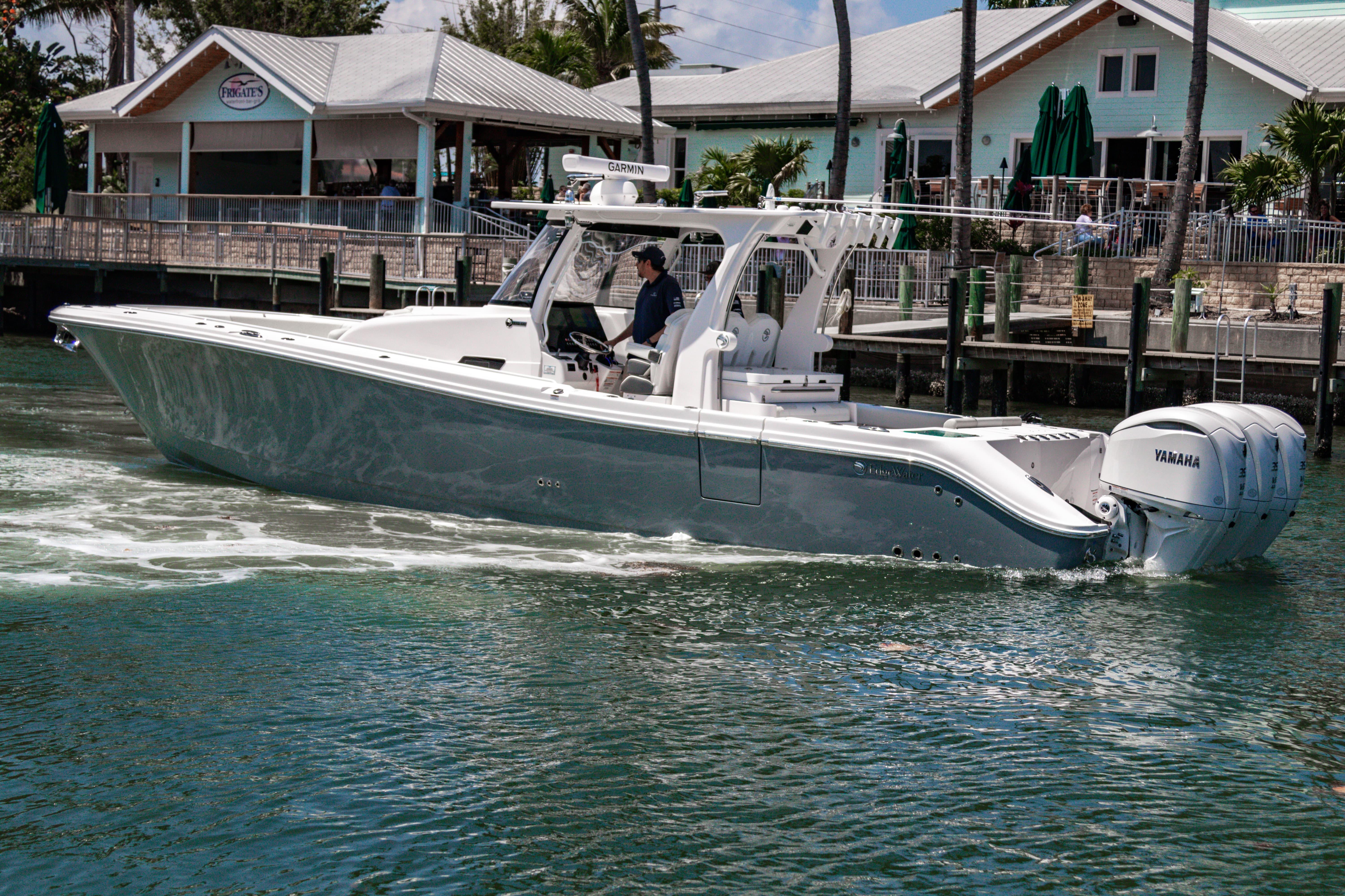 2025 Edgewater 370CC boat cruising near a marina with Yamaha engines.