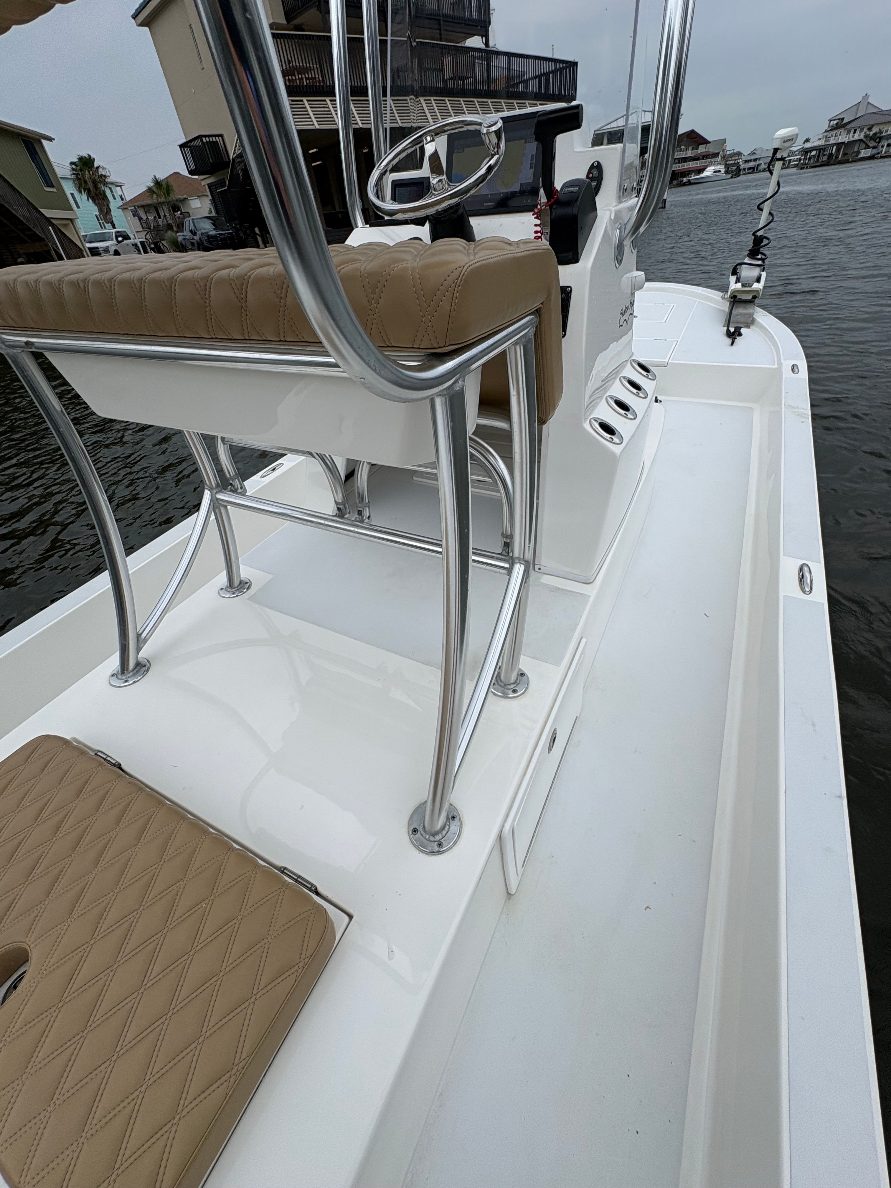 The image shows a modern boat with beige seats and stainless steel railings on the water.