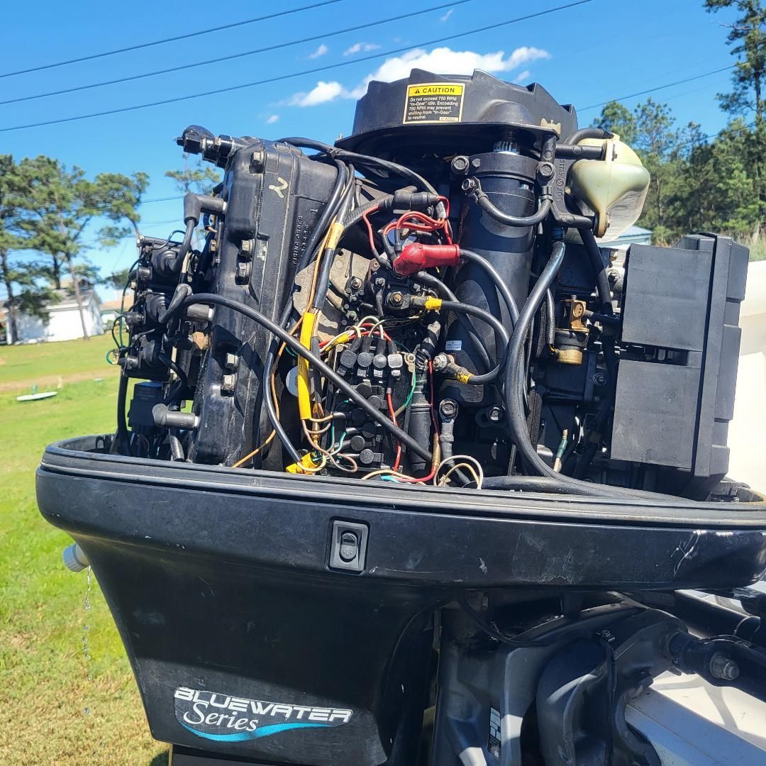 An outboard motor from the Bluewater Series is mounted on a boat. Wires and components are visible.