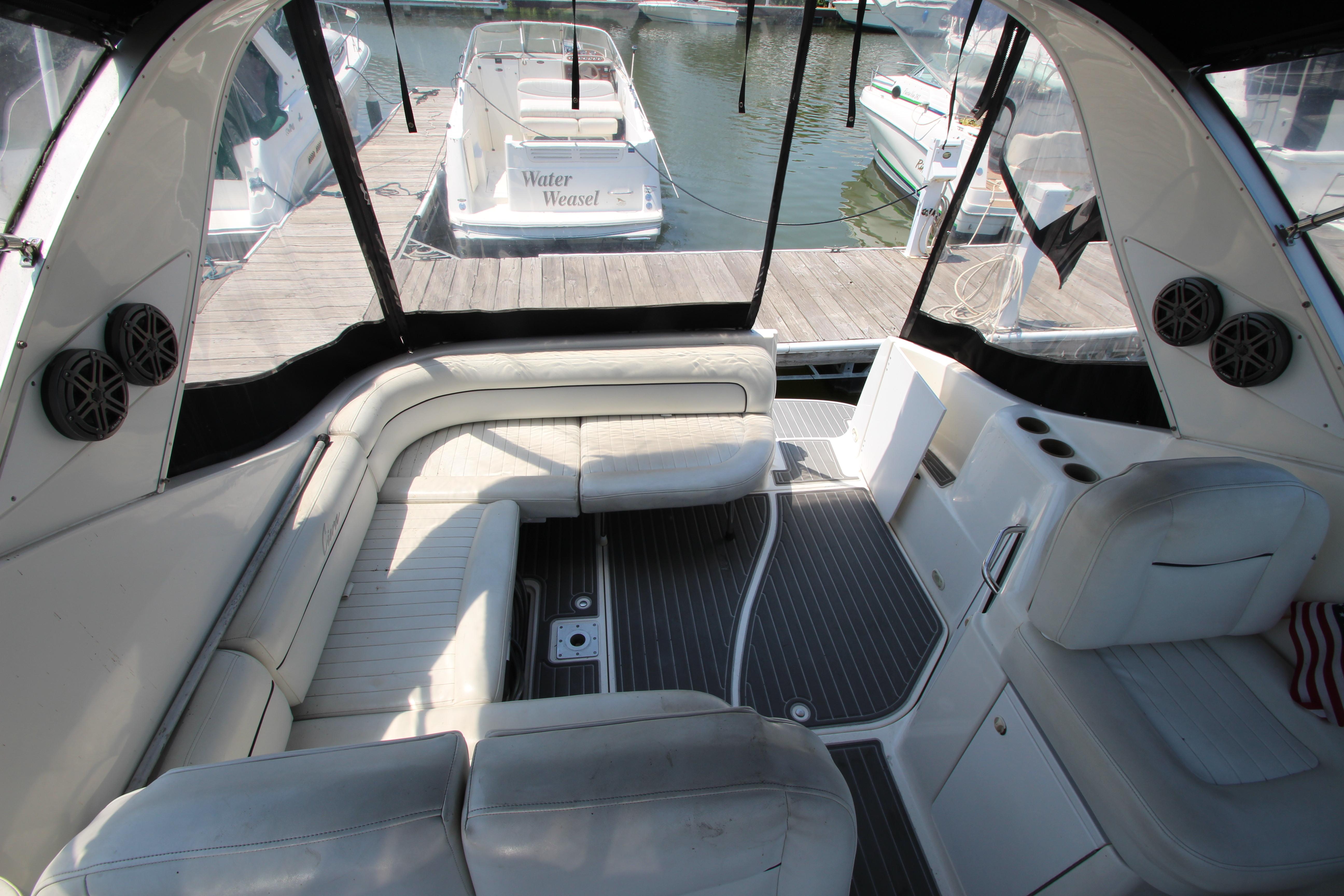 Interior view of 1999 Bayliner 3055 Ciera yacht with white seating and docked boats outside.