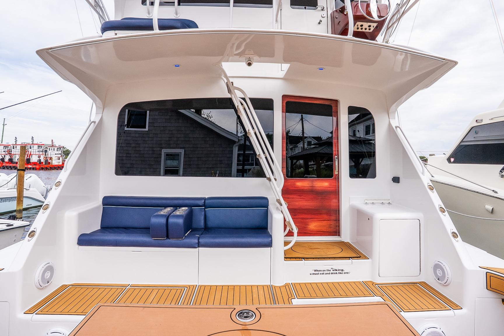 2002 Viking 61 Enclosed Bridge yacht with blue seating and wooden accents.