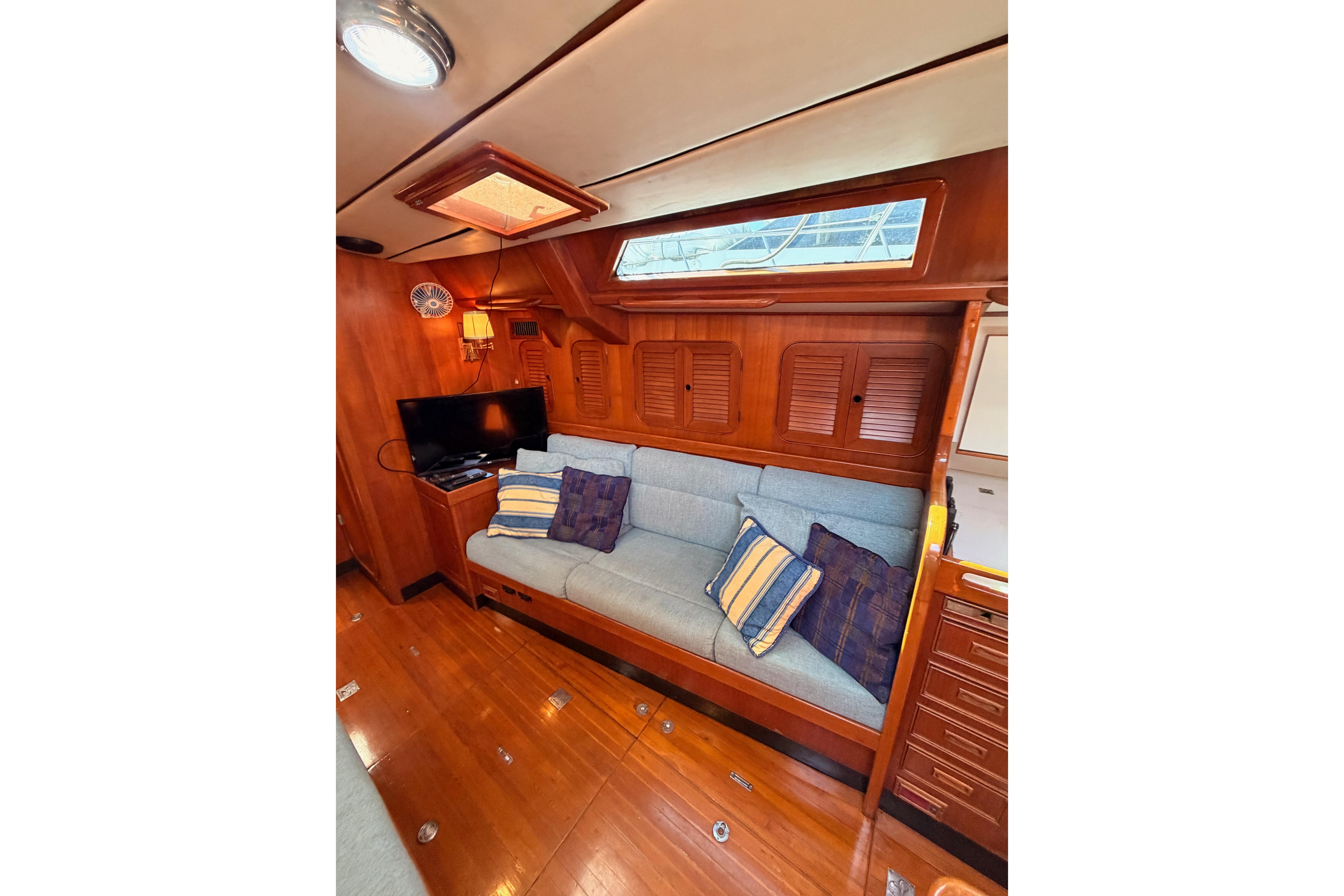 Interior of 1991 Hylas 51 yacht with cozy seating, wooden finish, and TV setup.