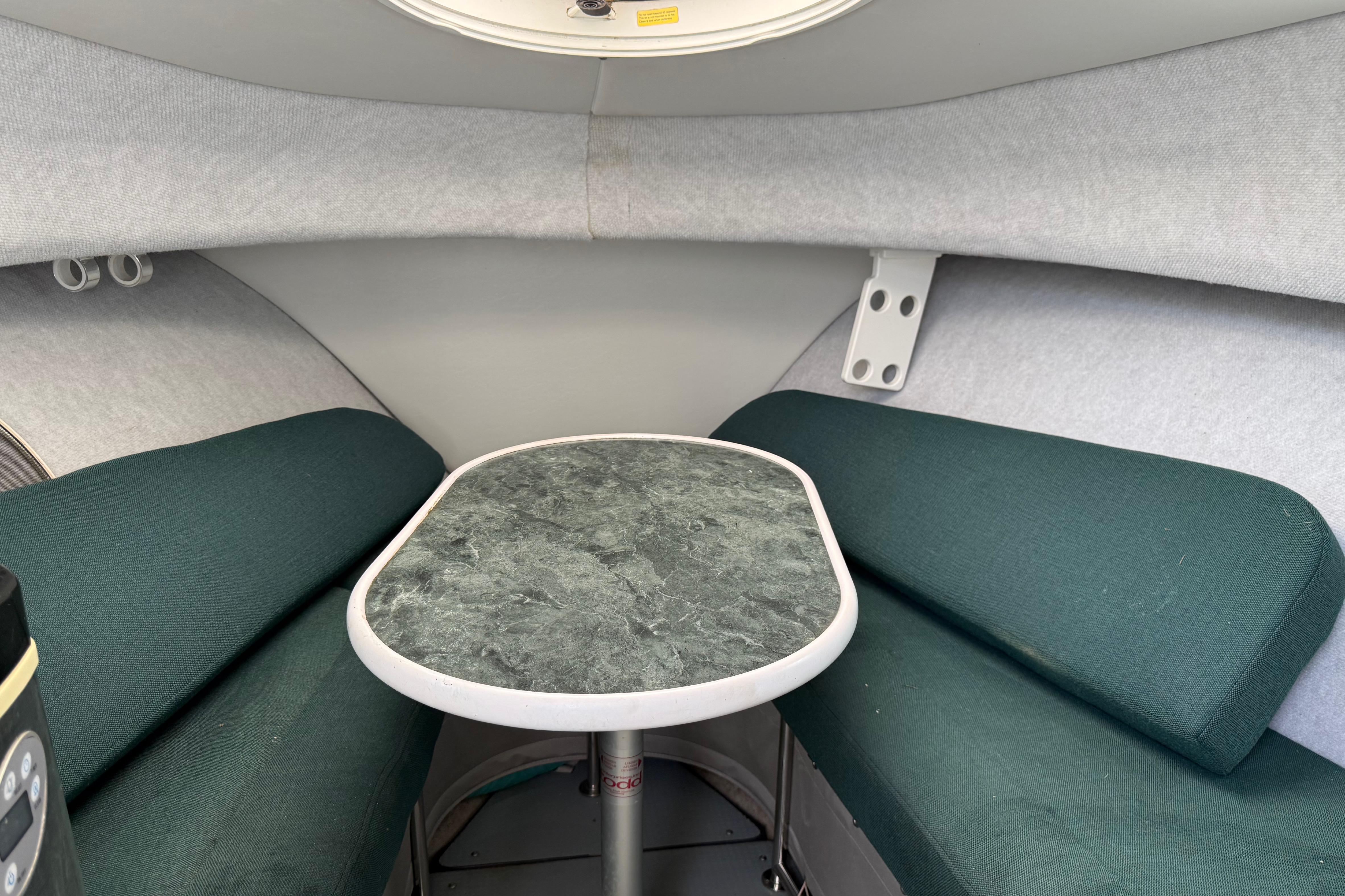 2006 Trophy 2502 Walkaround cabin interior with green seating and a central table.