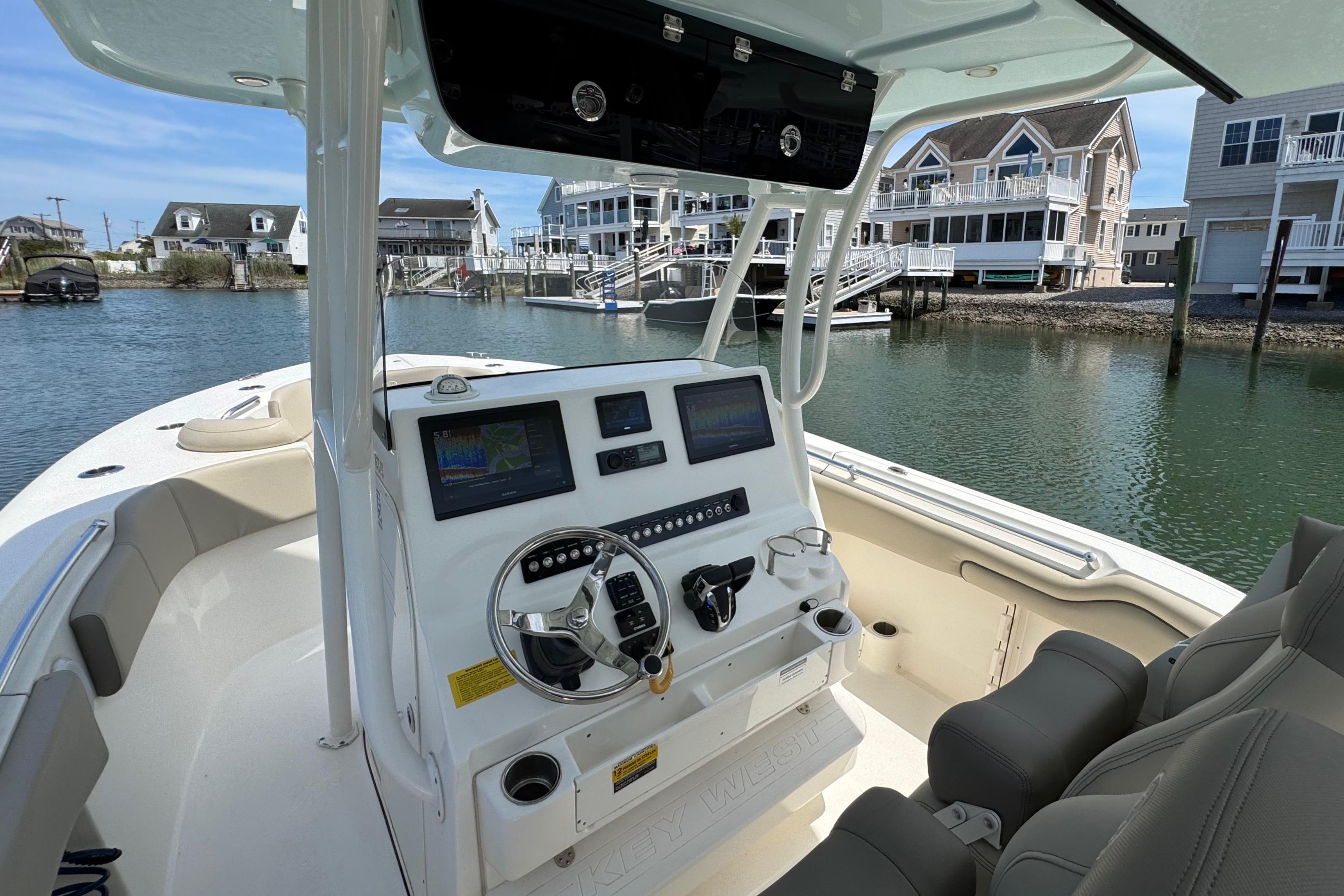 2022 Key West 263 FS boat interior with modern dashboard, docked near waterfront homes.