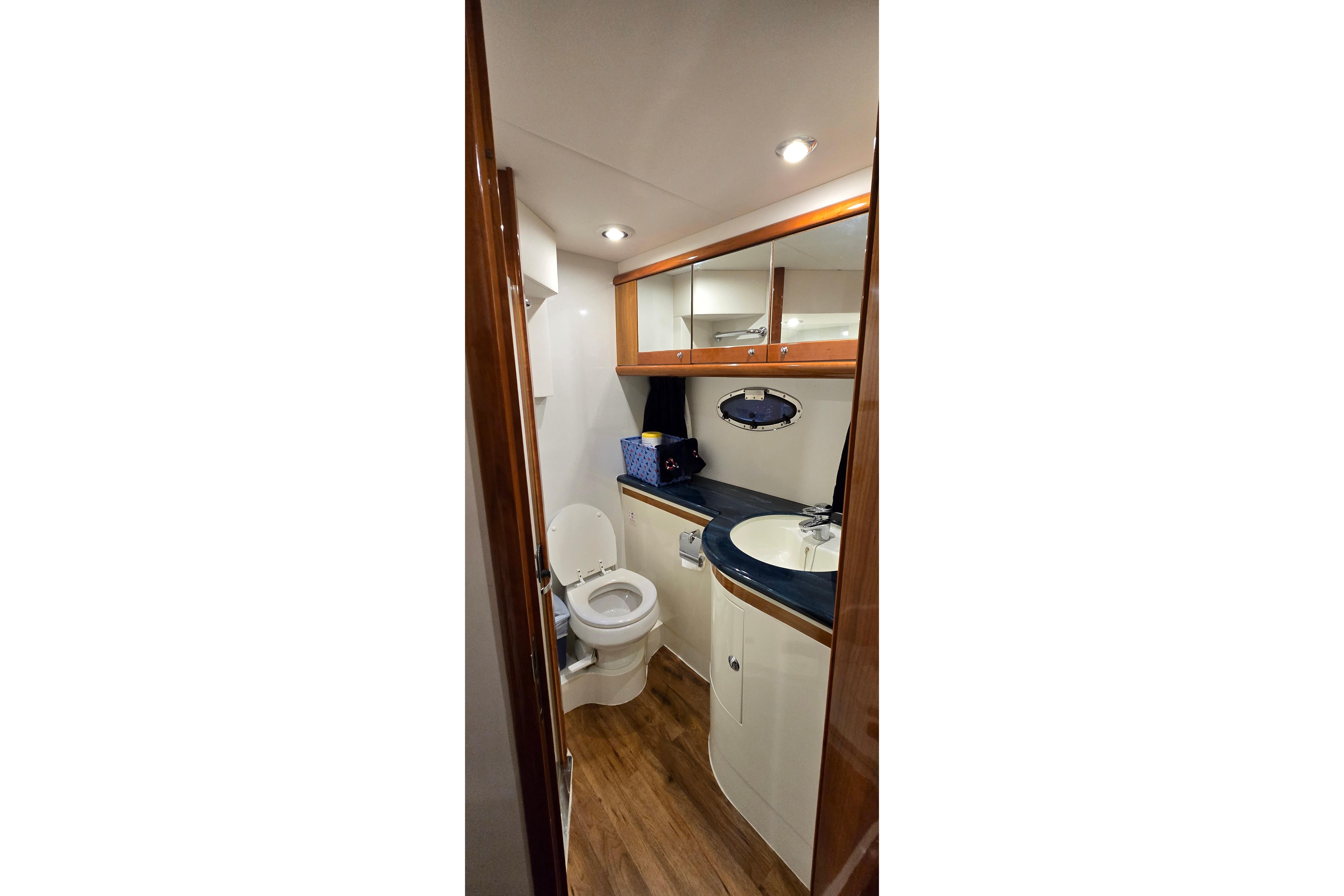Bathroom interior of 2004 Sunseeker Camargue 50 yacht, featuring wood accents and modern fixtures.
