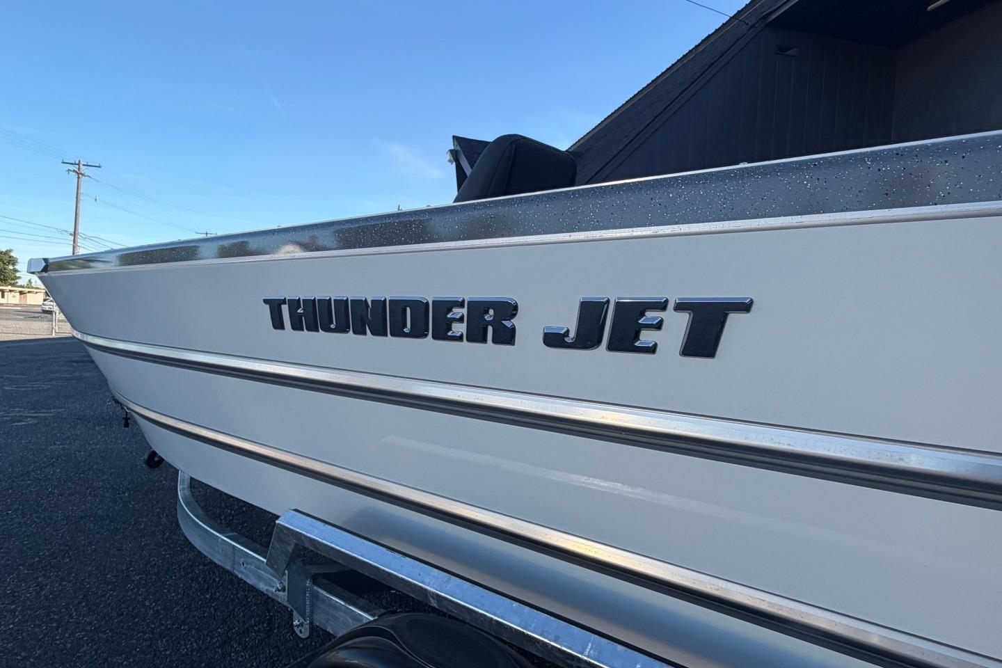 2026 Thunder Jet 209 Rush OT boat side view with logo, parked outdoors.