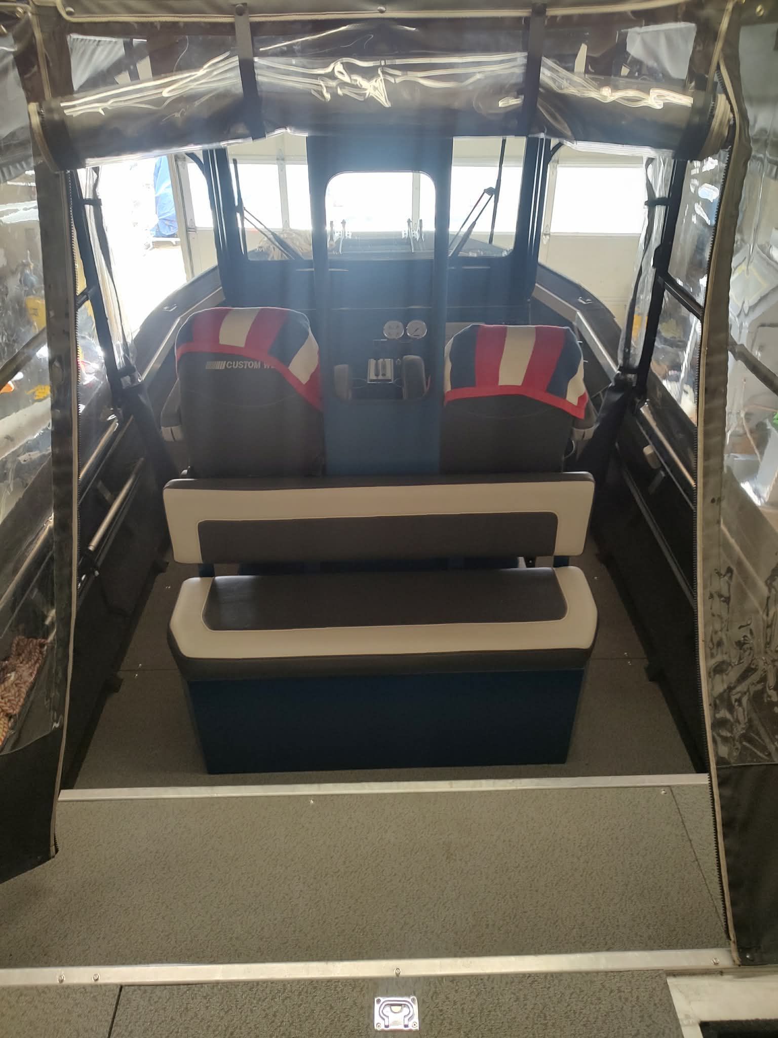Interior view of a Custom Weld 23' sled t-top boat with seating and helm.