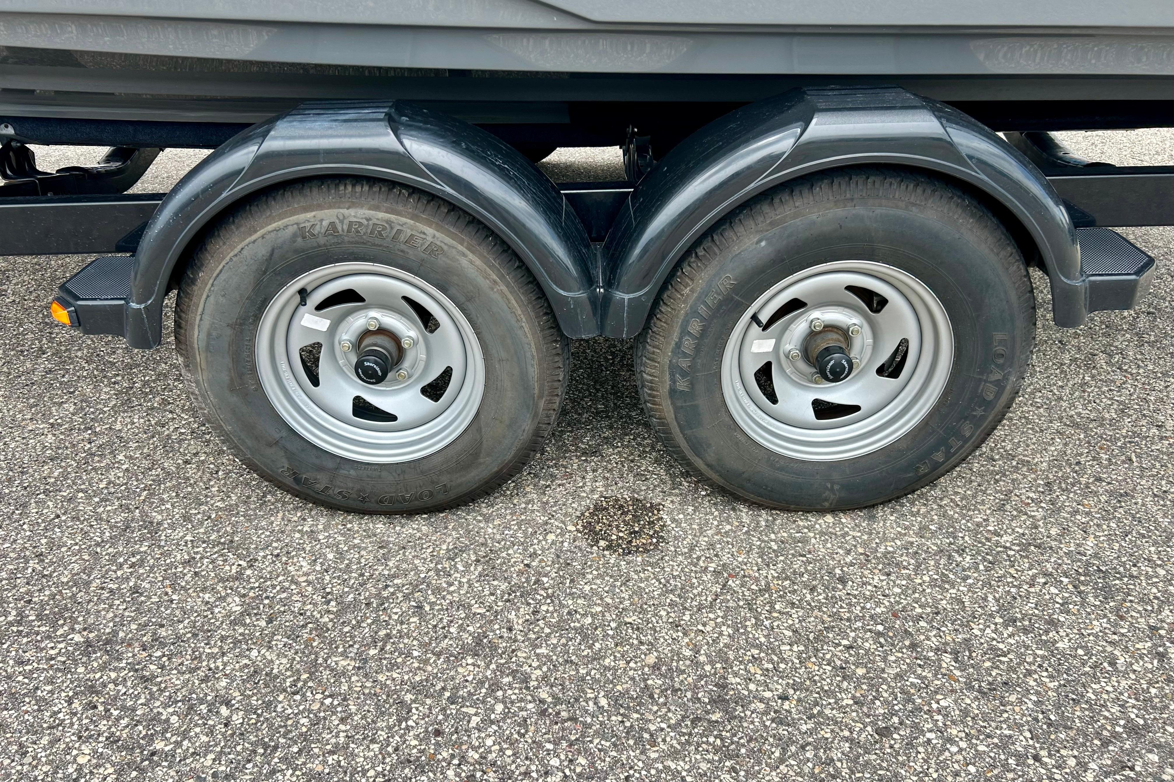 Trailer wheels of a 2015 Yamaha Boats AR210 on asphalt surface.