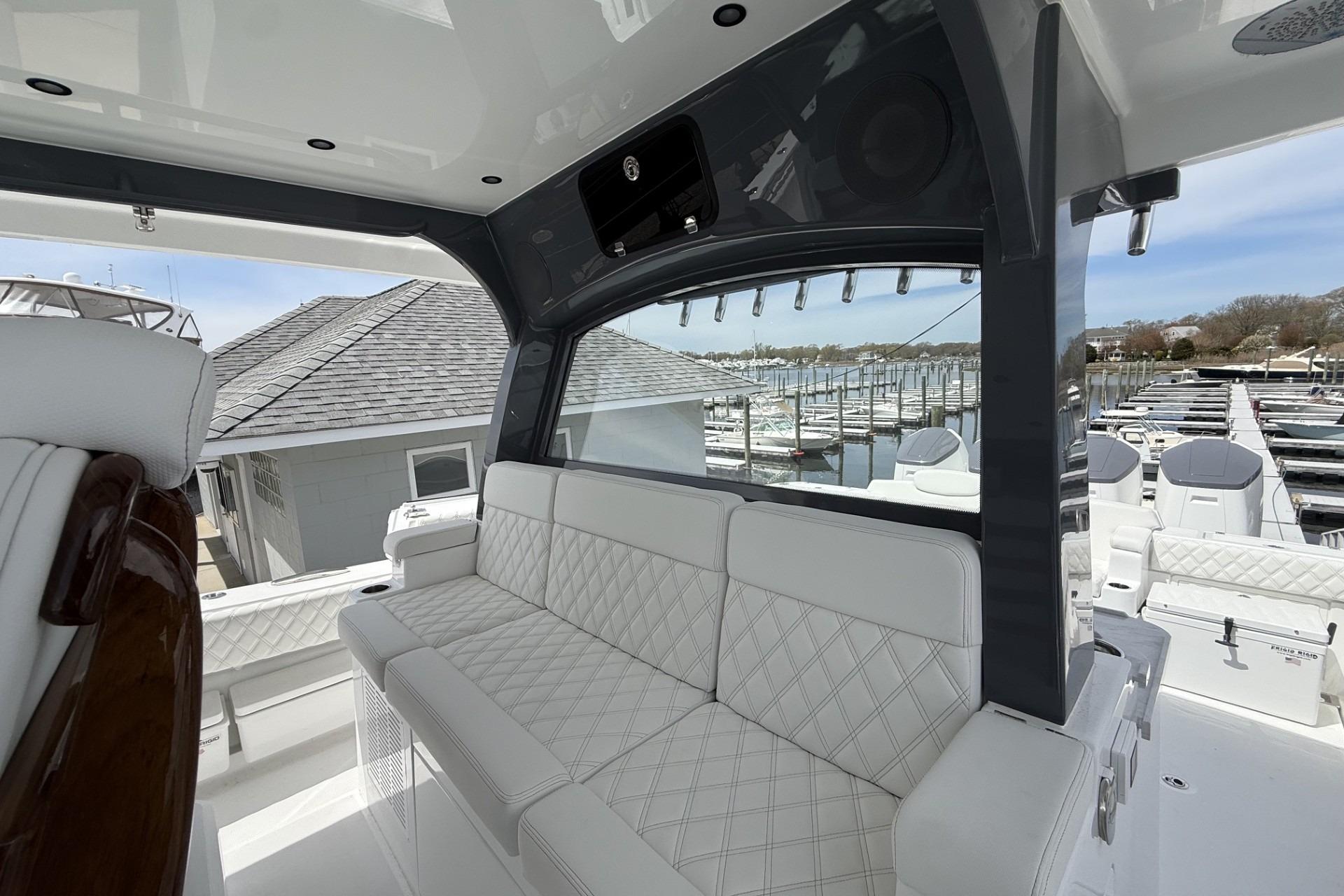 Luxurious interior of 2027 HCB 48 Campeon yacht with white seating and marina view.