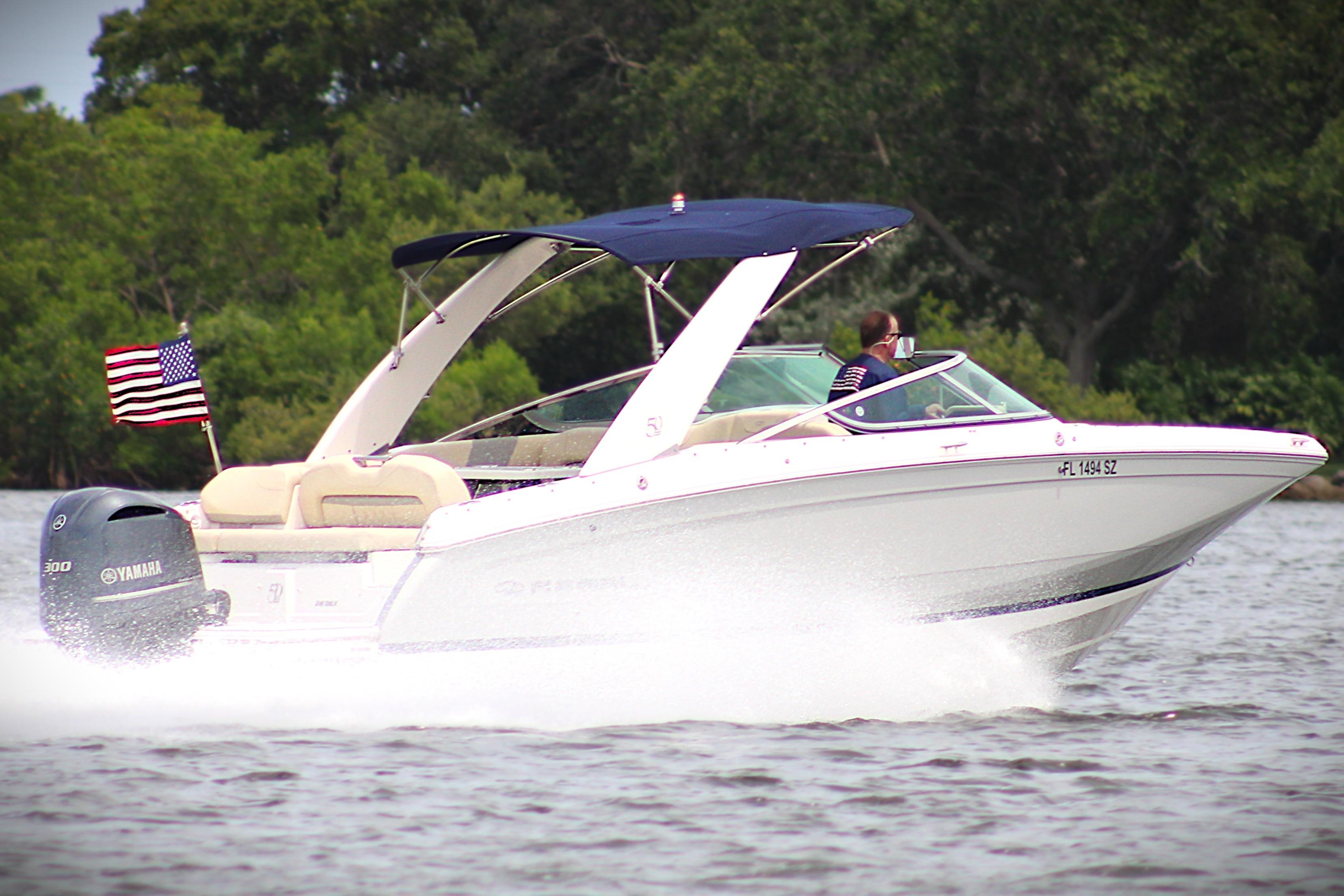 2021 Regal 26 OBX boat cruising on water with American flag and Yamaha engine.