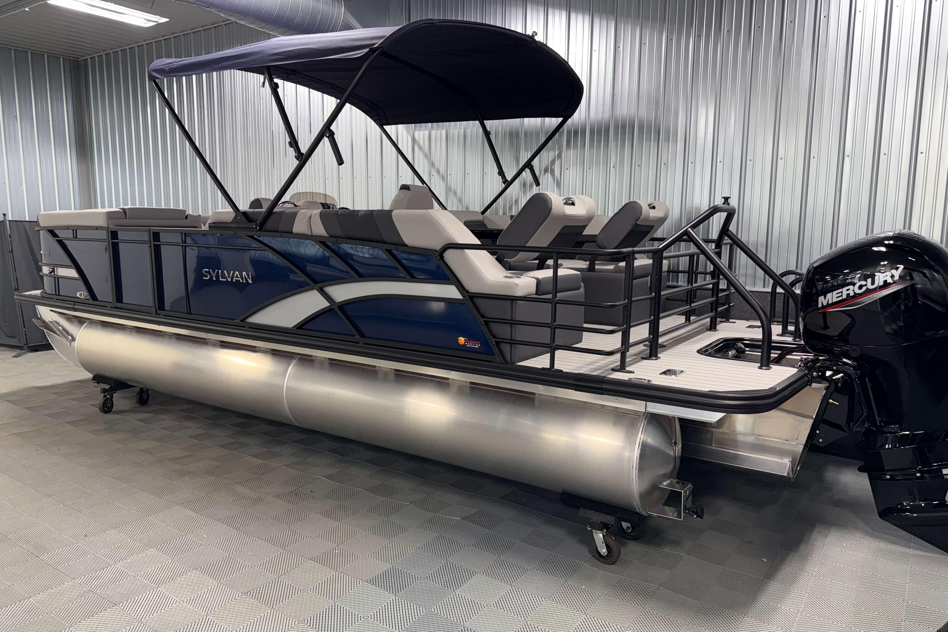 2026 Sylvan L3 SLZ pontoon boat with Mercury engine in a showroom.