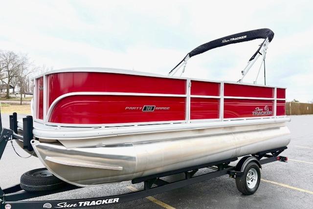 2026 Sun Tracker Party Barge 18 DLX pontoon boat on trailer, red and silver design.
