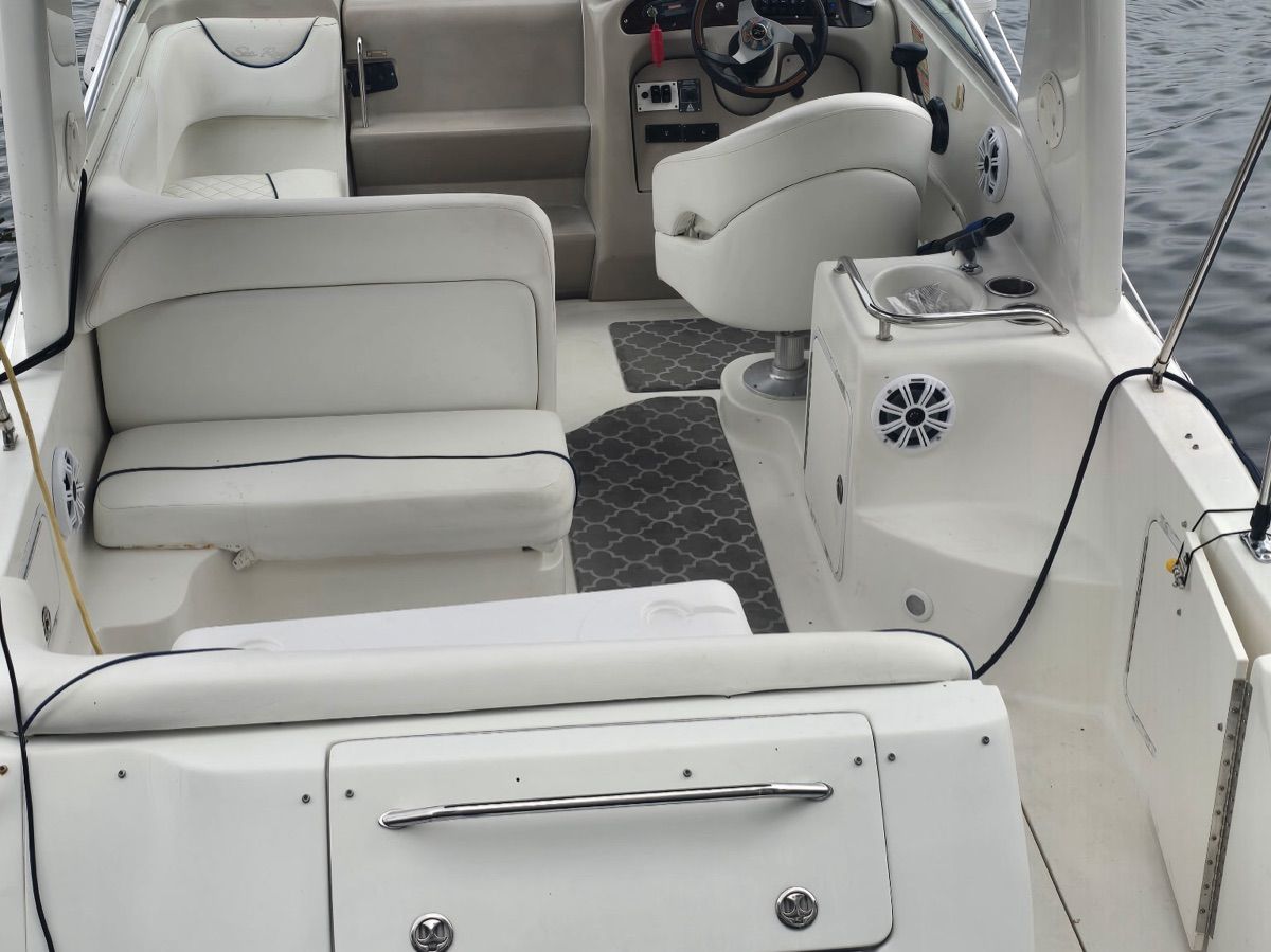 The interior of a Sea Ray Sundancer 260 boat with white seating and gray carpet.