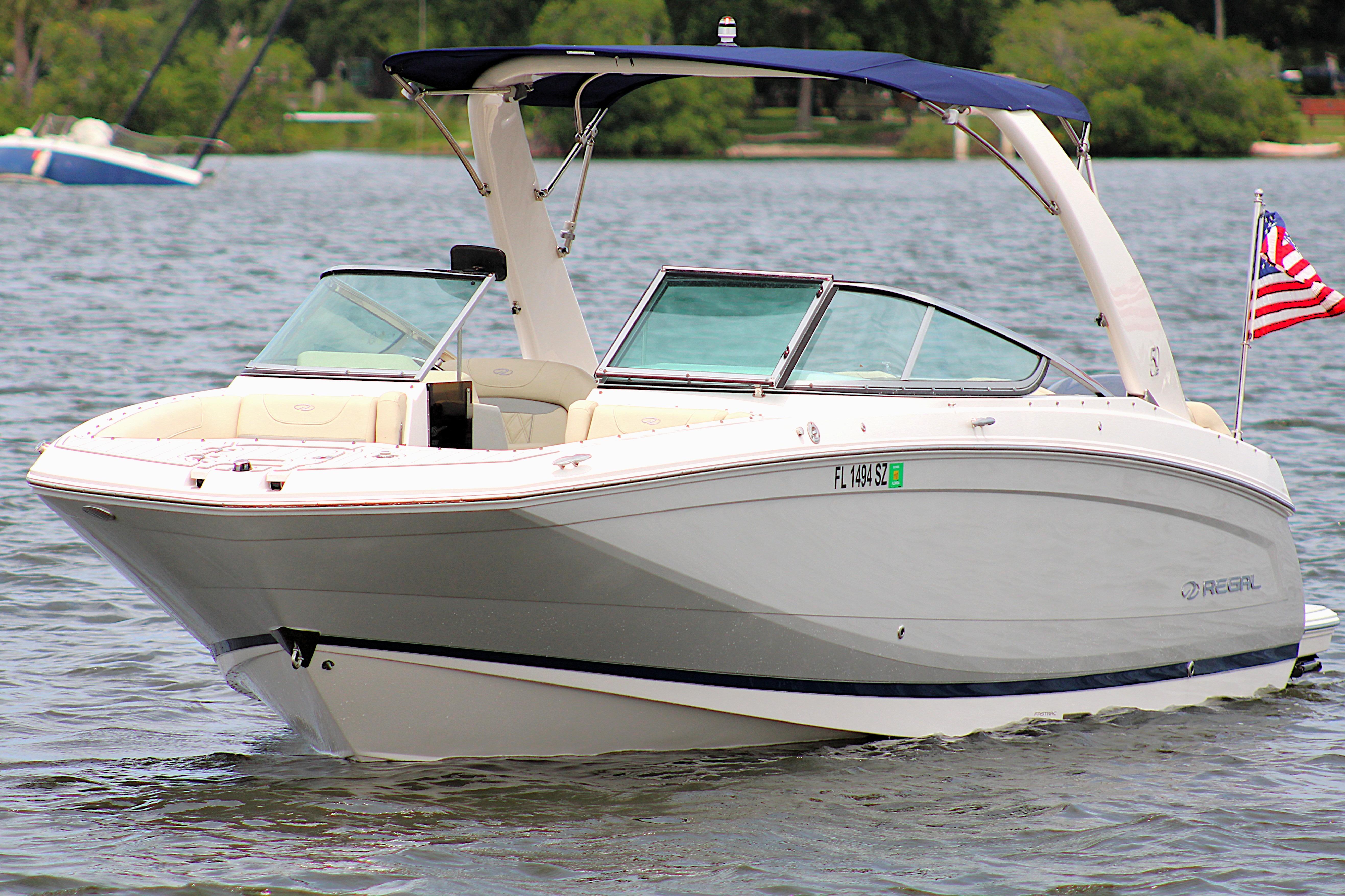2021 Regal 26 OBX boat on a lake with American flag, sunny day.