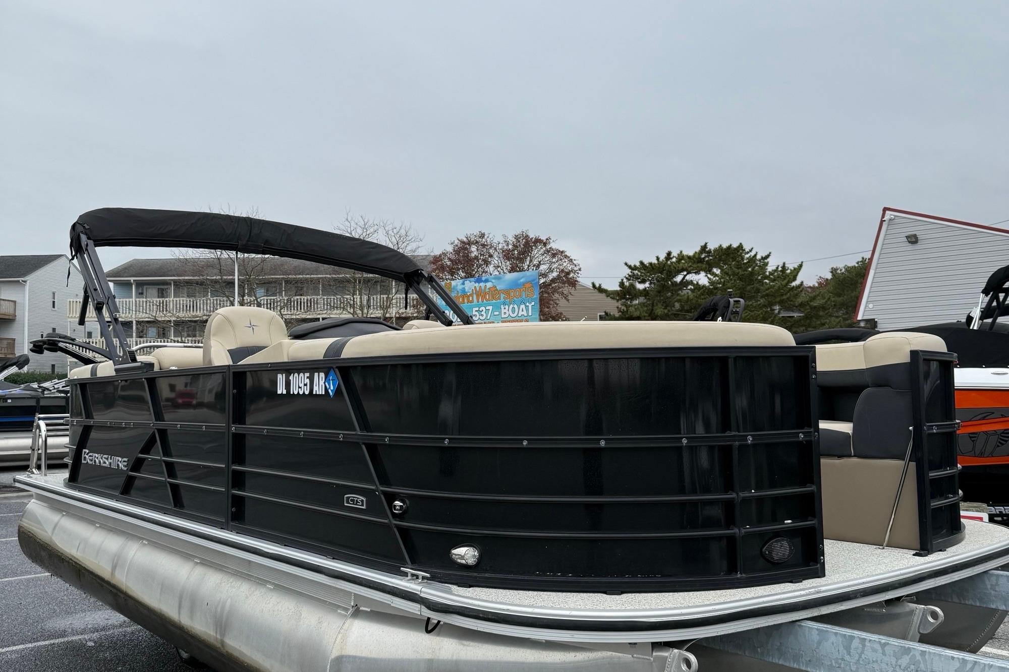 2024 Berkshire 22RFX CTS pontoon boat with black exterior and beige seating, parked outdoors.