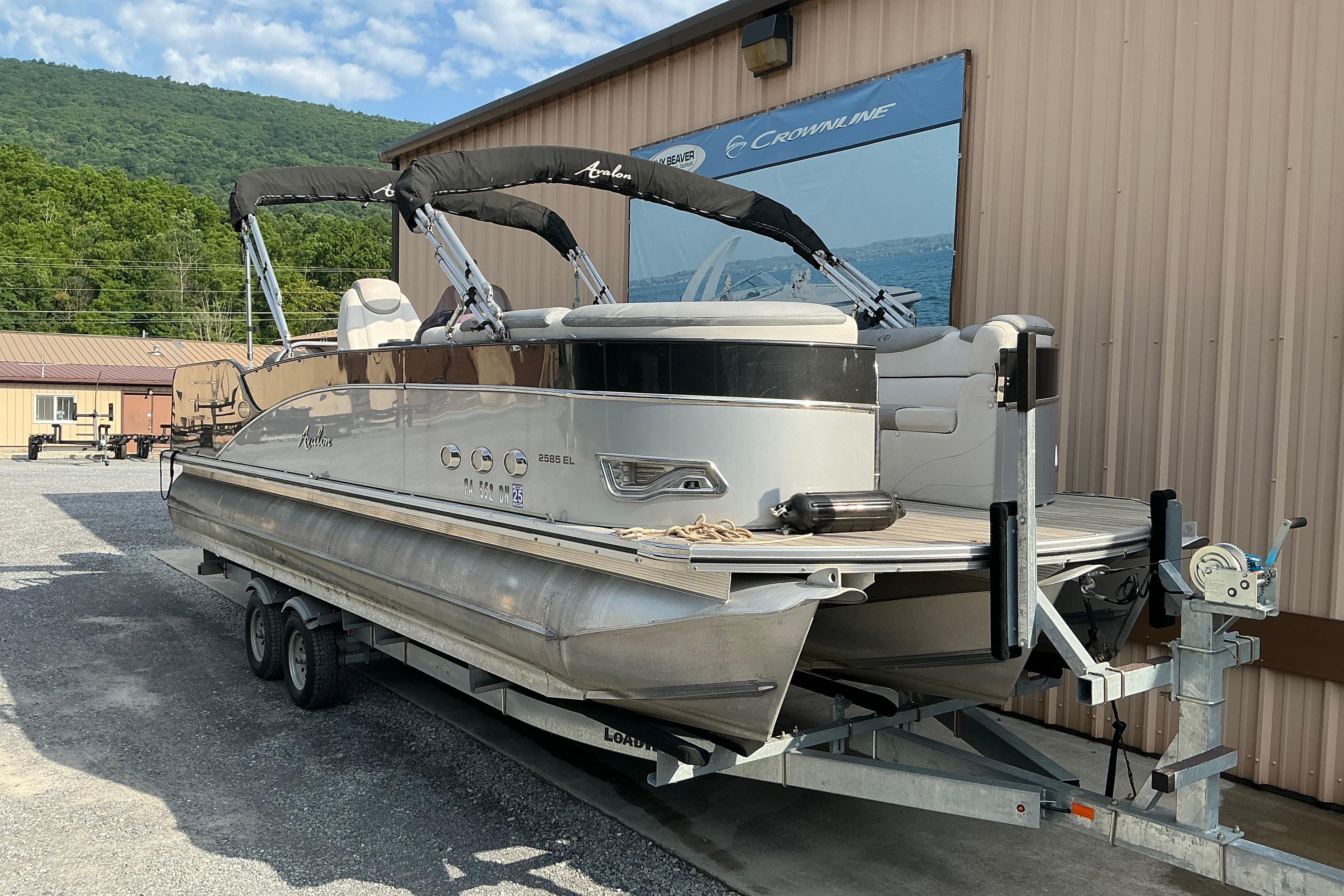 2014 Avalon 25 ft. Paradise Elite pontoon boat on trailer near building.
