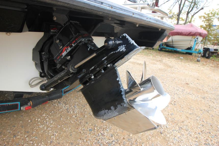 1989 Formula 223 SS boat outdrive with stainless steel propeller on gravel surface.