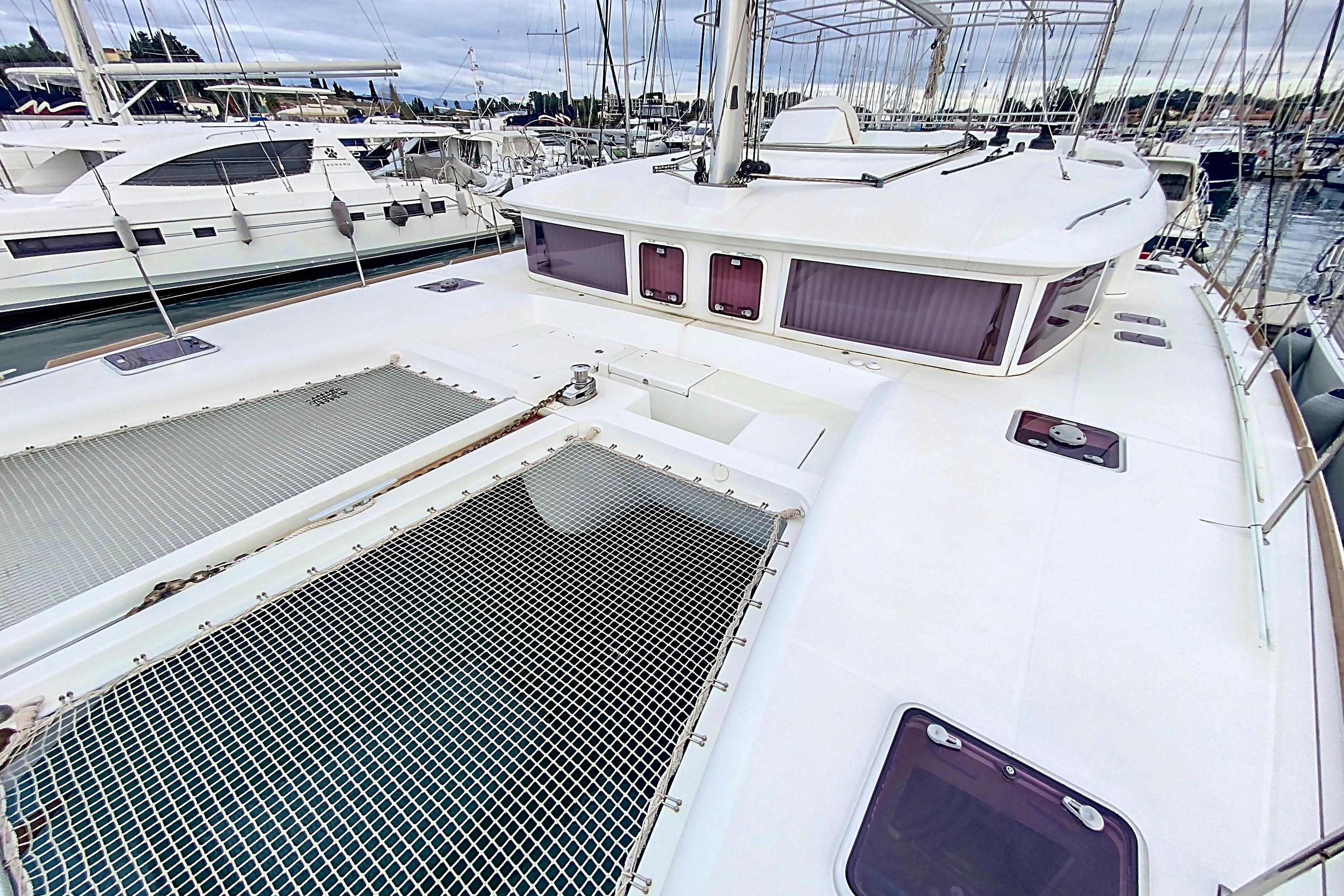 2011 Lagoon 450 catamaran docked at marina, showcasing spacious deck and netting.