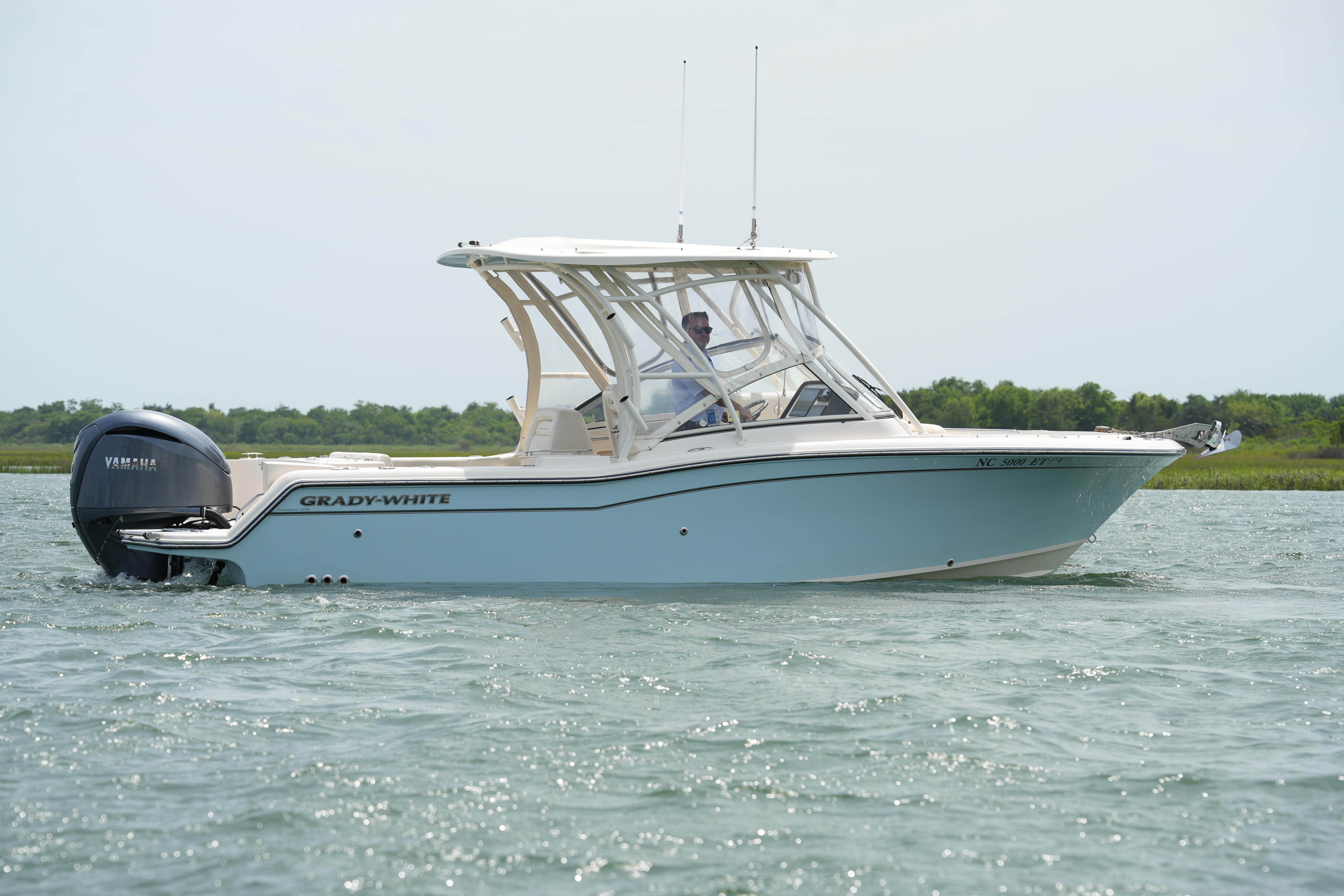 2021 Grady-White Freedom 235 boat cruising on calm waters with lush greenery in the background.
