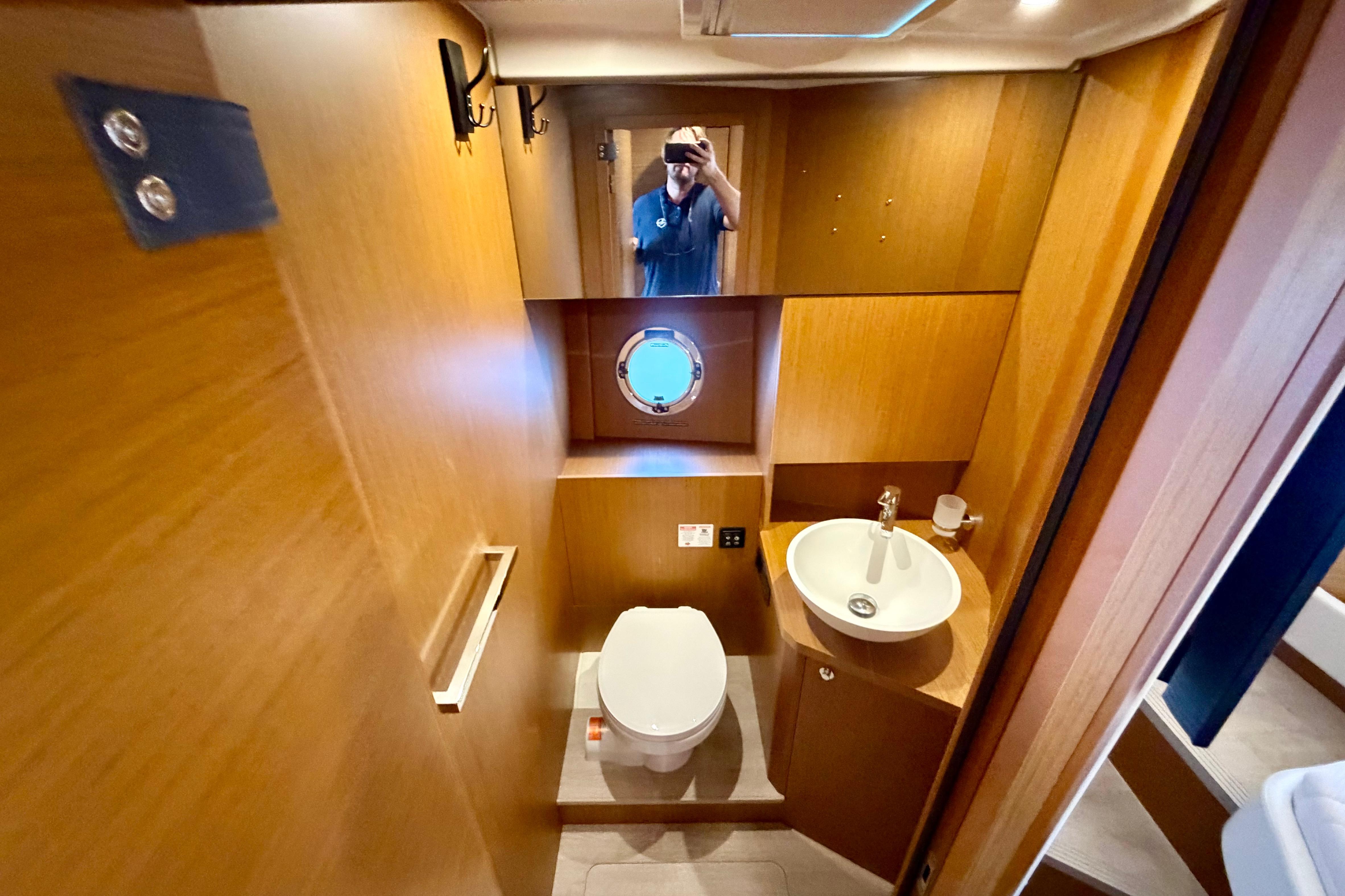 Bathroom interior of 2025 Beneteau Swift Trawler 41 Fly, featuring modern fixtures and wood paneling.