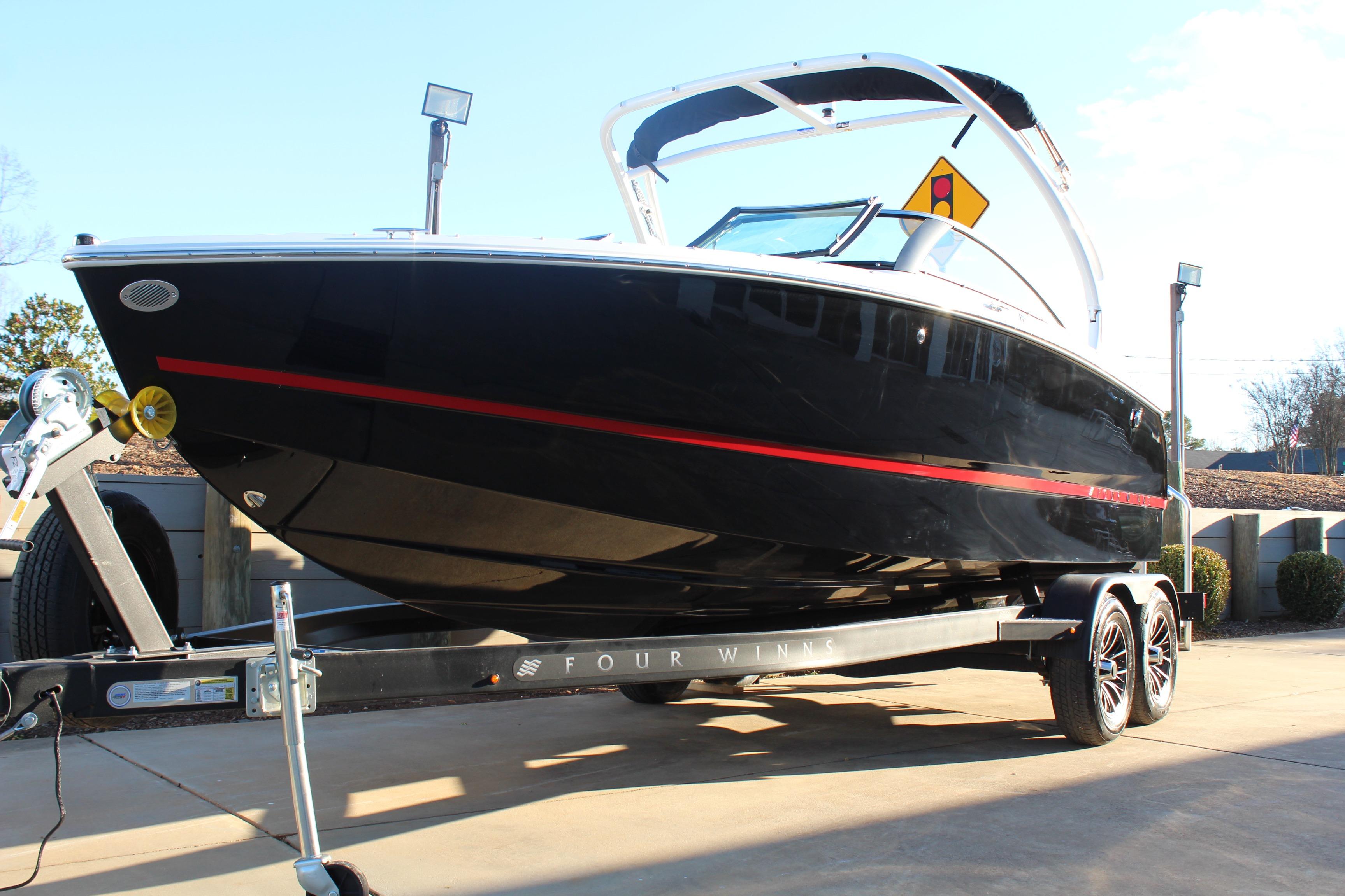 2026 Four Winns H2 Freedom boat on trailer, sleek black design with red accents.