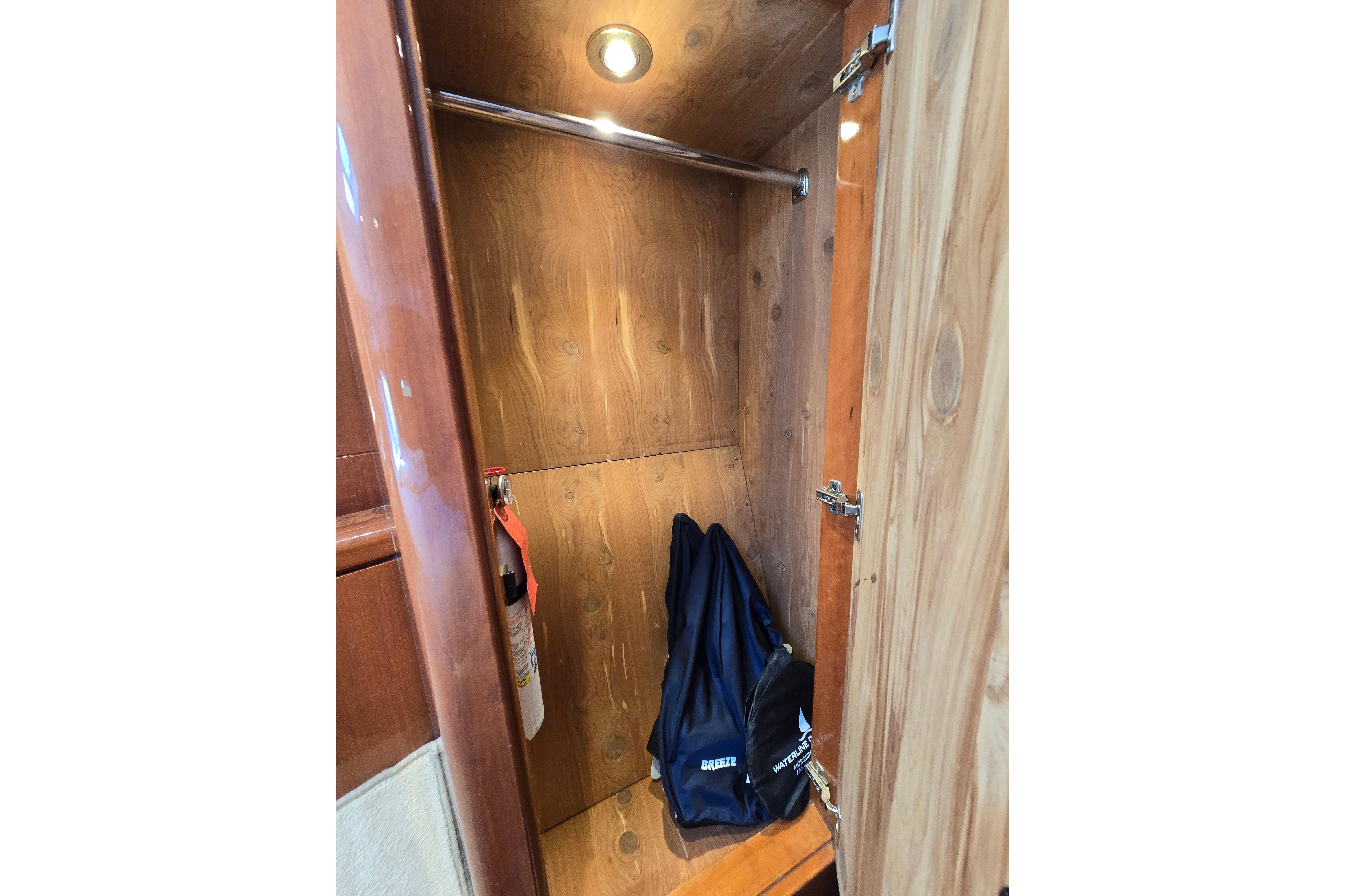 Wooden closet interior on a 2004 Grand Harbour 58 yacht, featuring a hanging rod and storage bag.