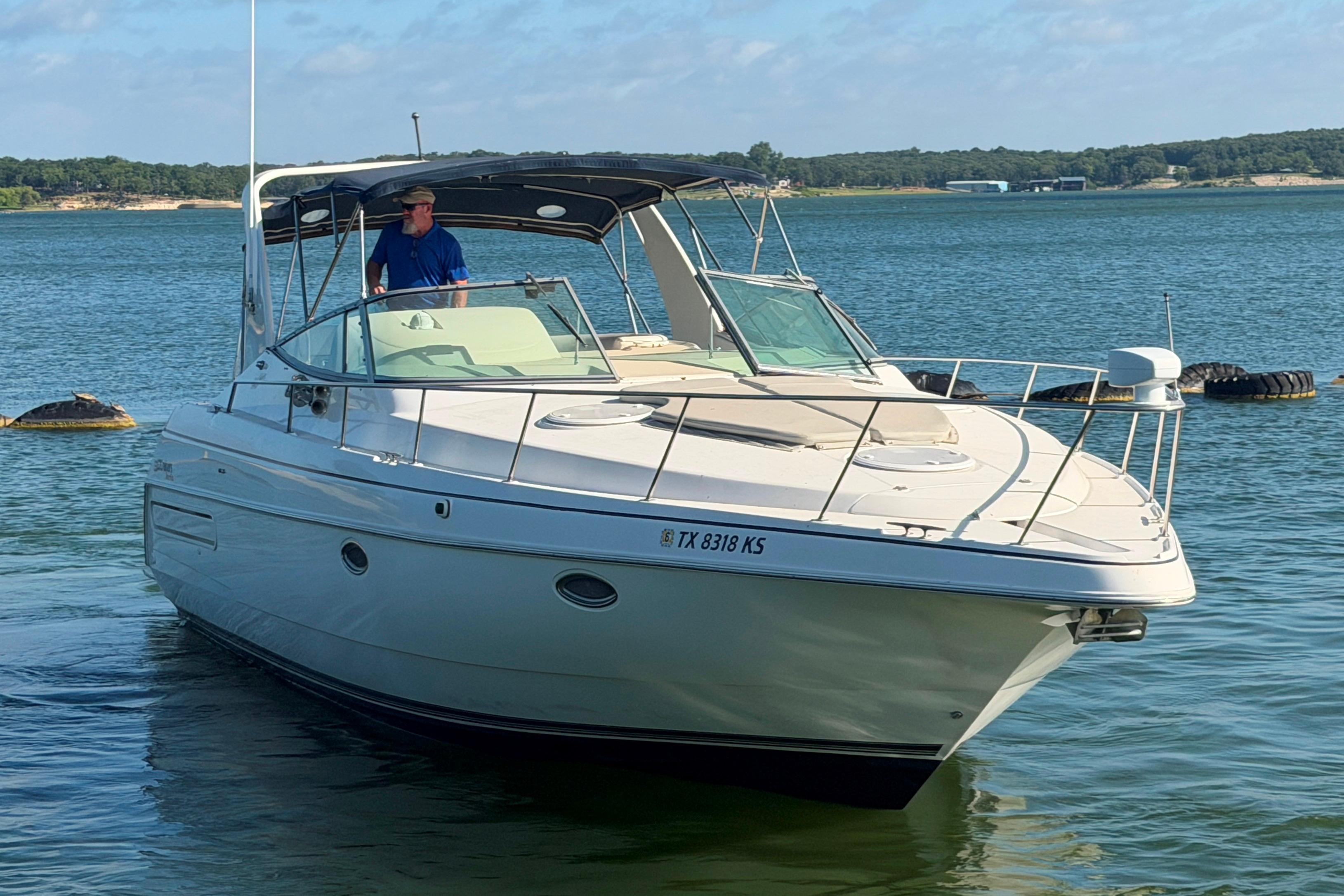 1997 Cruisers 3575 yacht on a serene lake with a person at the helm.
