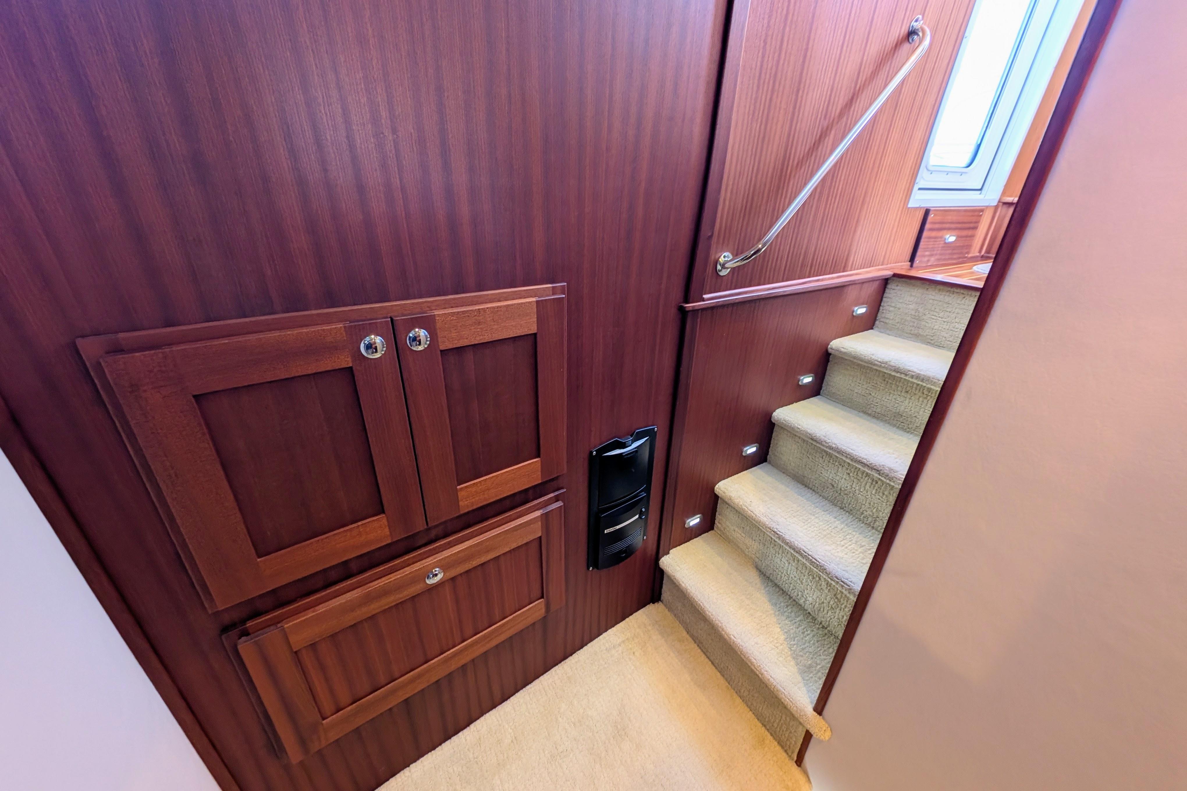 Interior of 2015 American Tug 435 with wooden cabinetry and carpeted stairs.