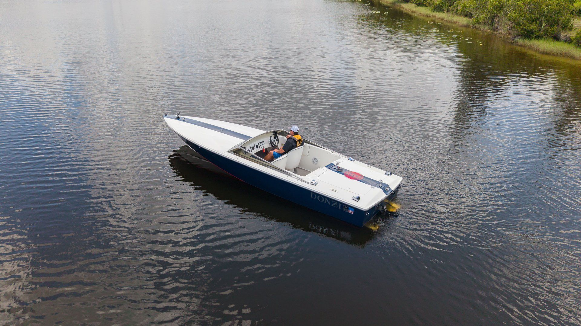 A blue and white motorboat cruises on calm water.