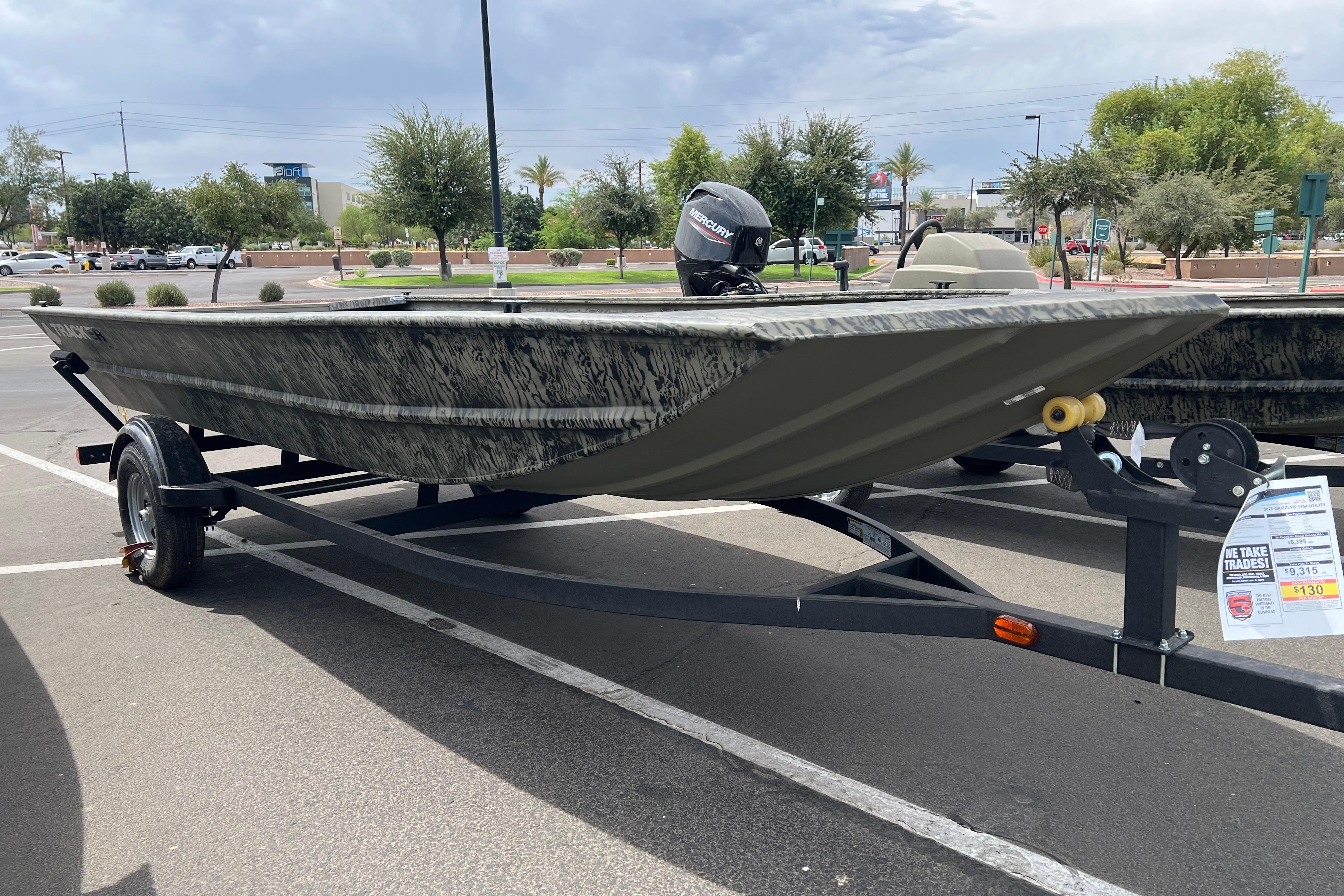 2026 Tracker Grizzly 1754 Utility boat on trailer in parking lot.