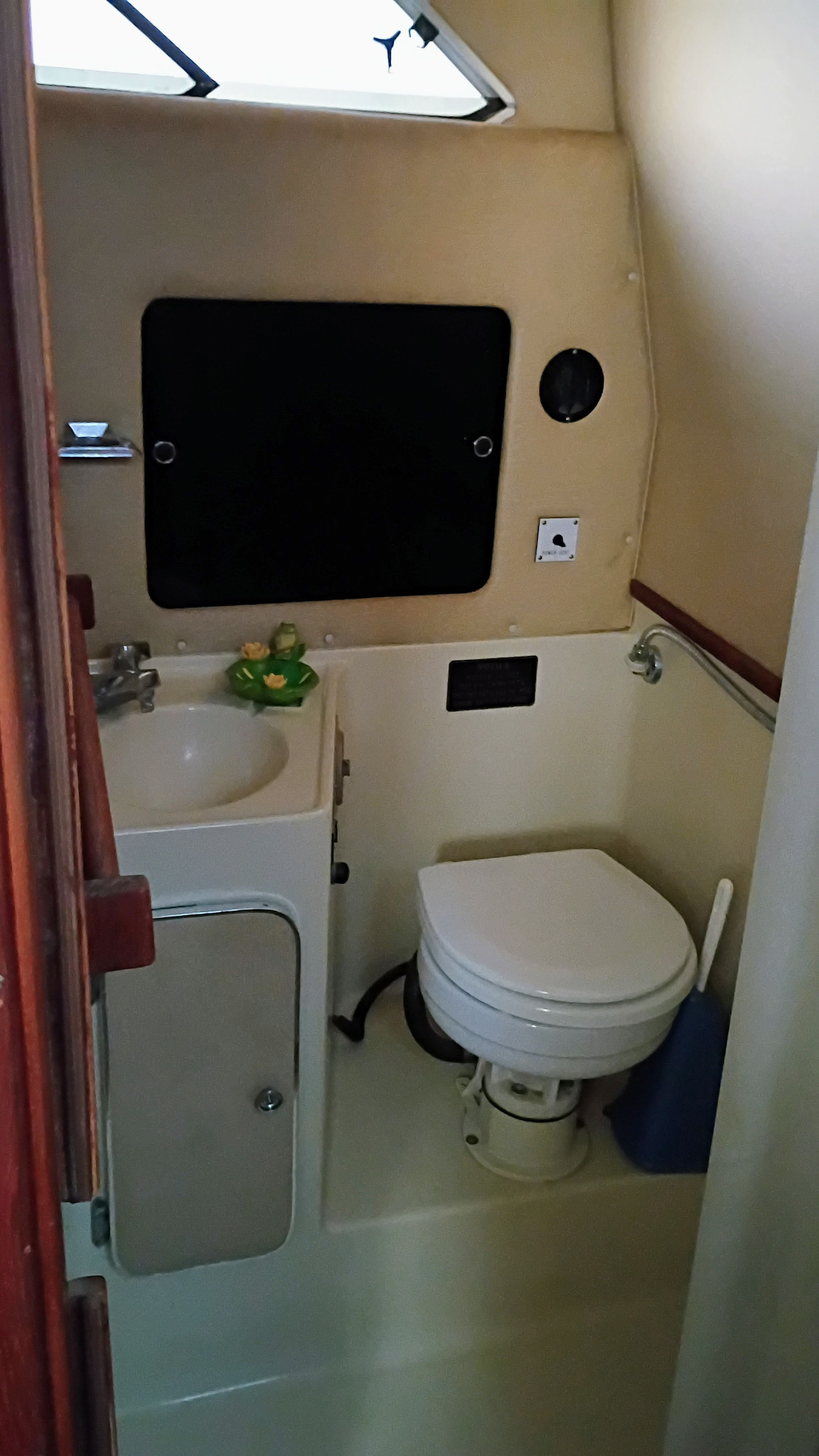 The image shows a boat bathroom with a toilet, sink, and small window.