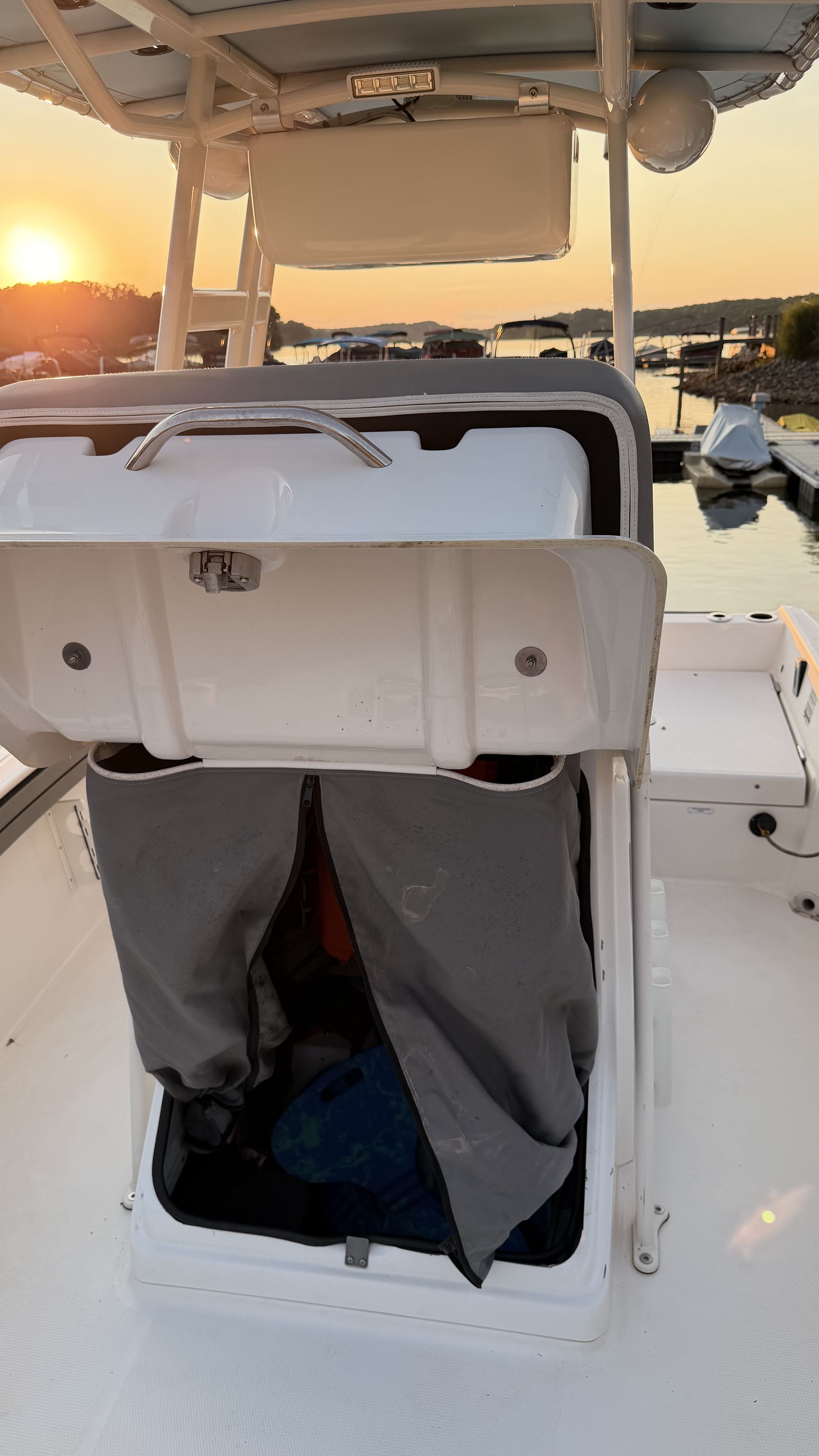 An open storage compartment on a boat with a sunset in the background.