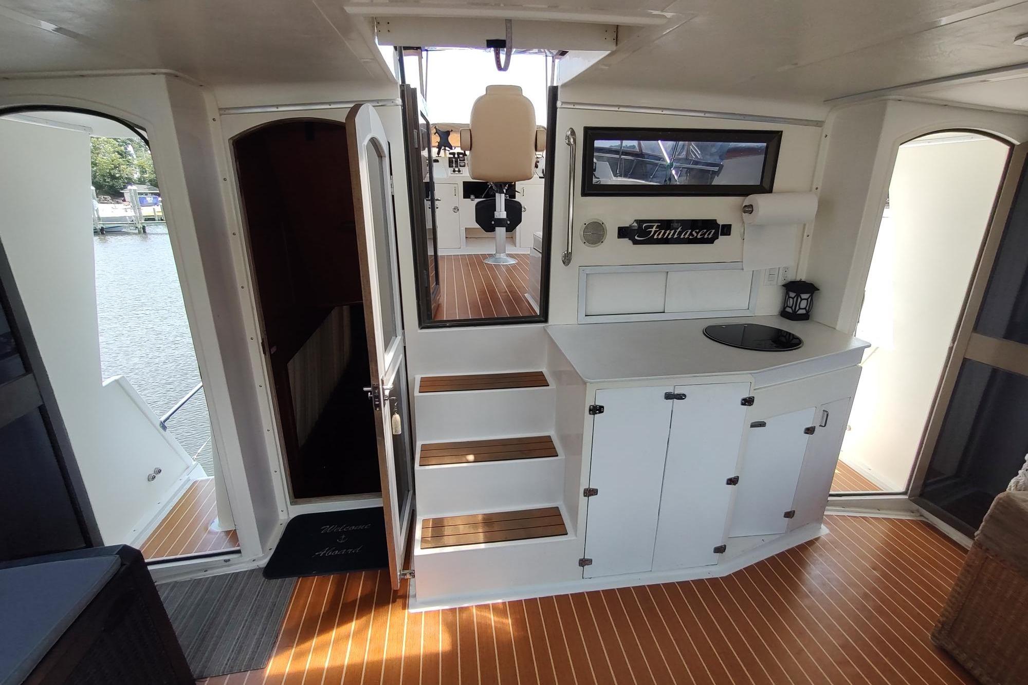 Interior of 1989 Hyatt Double Cabin Motoryacht with wooden flooring and white cabinetry.