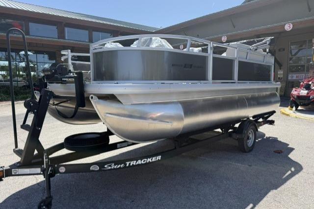 2026 Sun Tracker Bass Buggy 16 XL Select pontoon boat on trailer, parked outdoors.