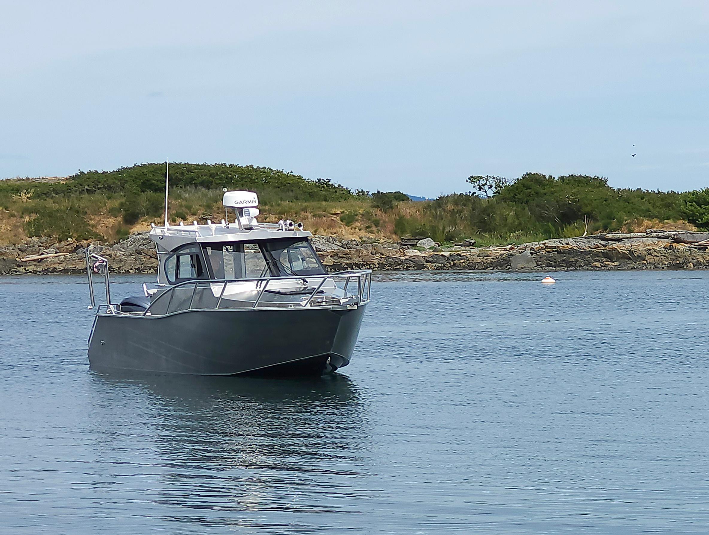 2024 Gospel Boat Profisher 750 on calm water near a rocky shoreline.