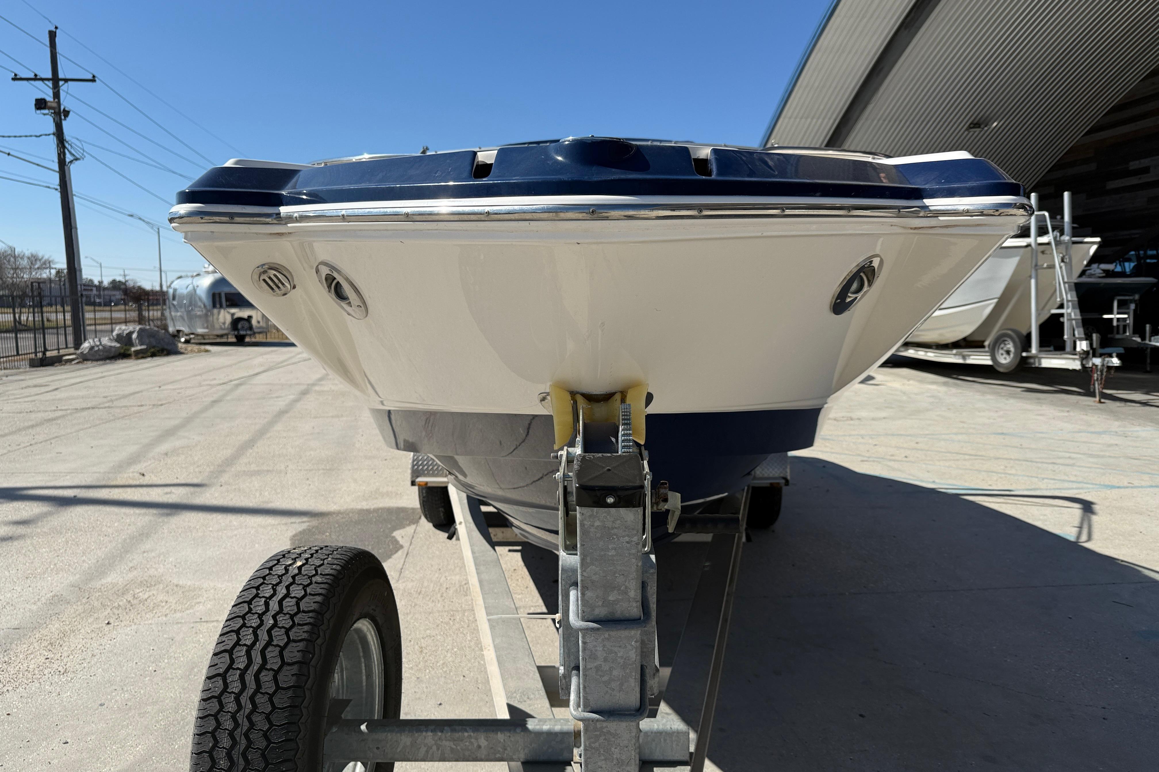 2014 Chaparral 264 Sunesta boat on trailer, parked outdoors under clear blue sky.