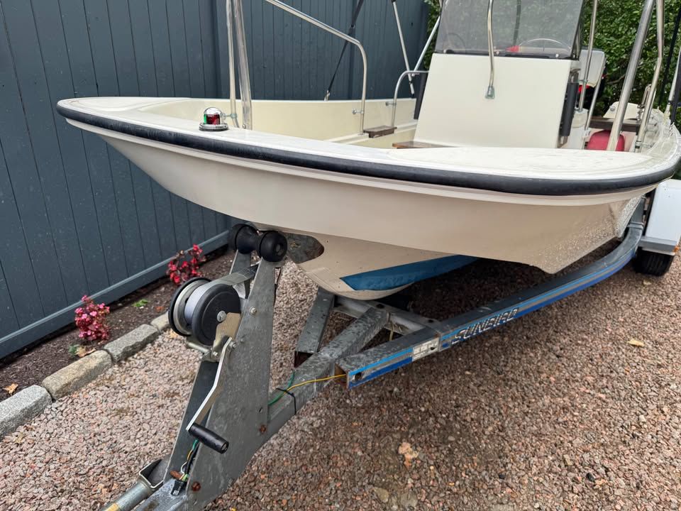 A 1976 Boston Whaler 17 Montauk on a trailer, featuring a white hull with blue accents.