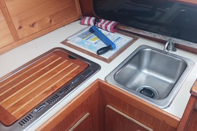 1989 O'Day 272 sailboat galley with sink, cutting board, and nautical chart.