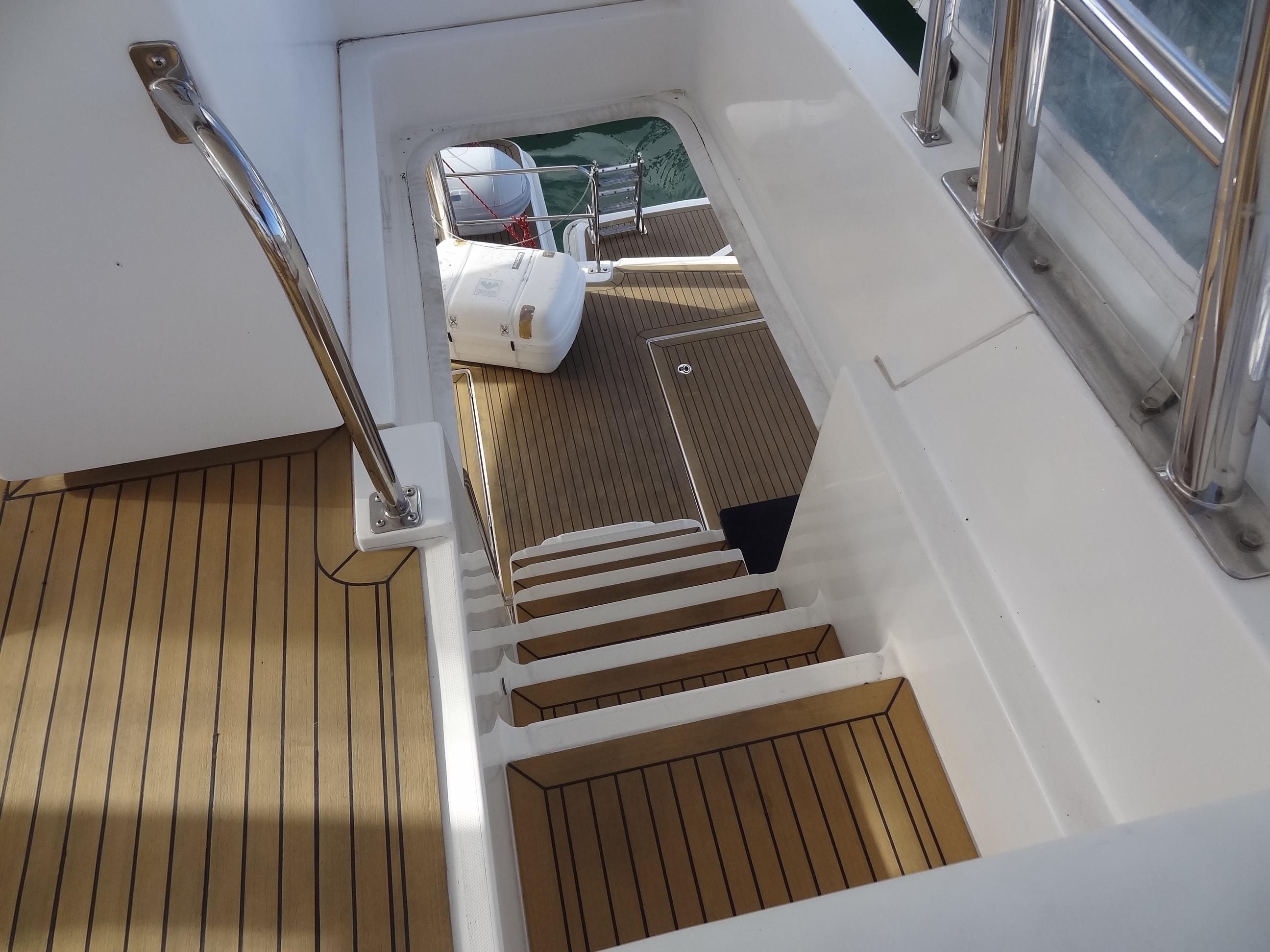 Staircase on 2014 Leopard 58 yacht with teak flooring and stainless steel handrails.