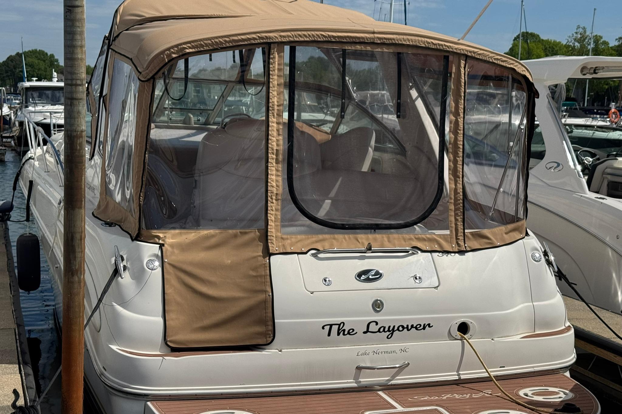 2001 Sea Ray 340 Sundancer docked, featuring tan canopy and clear windows.