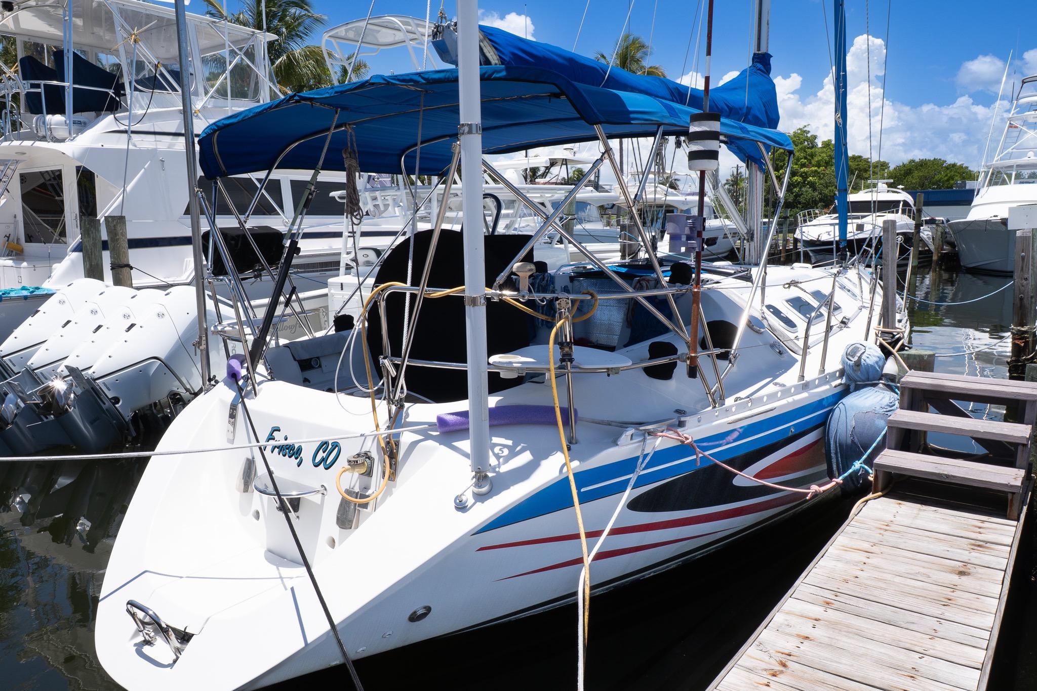 1993 Beneteau First 38 s5 sailboat docked, featuring blue canopy and vibrant hull design.