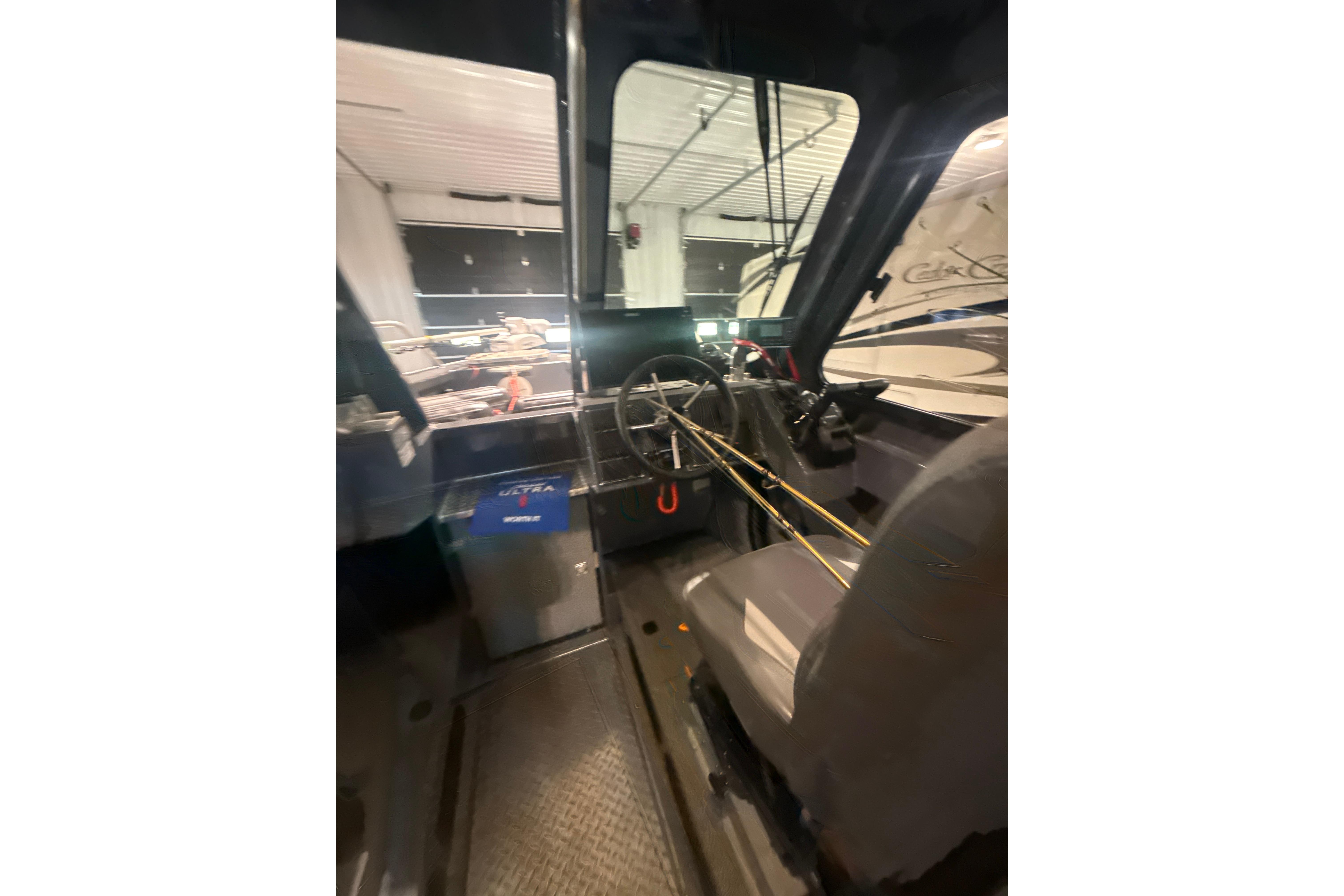 Interior view of 2022 Hewescraft 270 Alaskan Hardtop boat, showcasing steering and seating area.